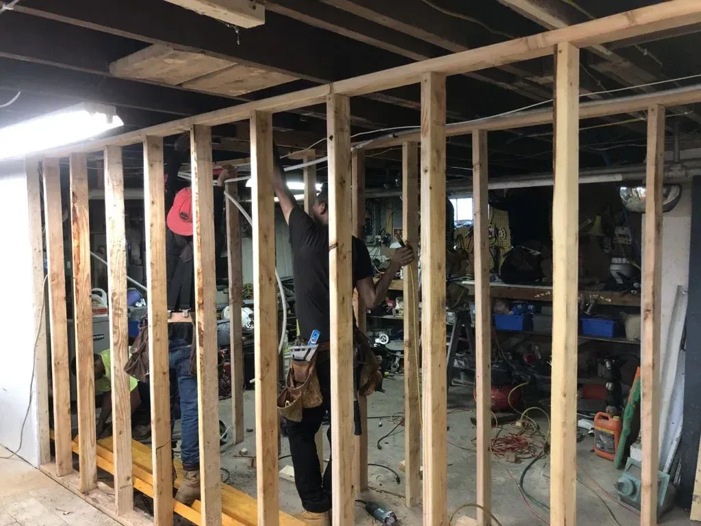 Partially framed basement with exposed wooden studs, tools, and work materials visible inside.