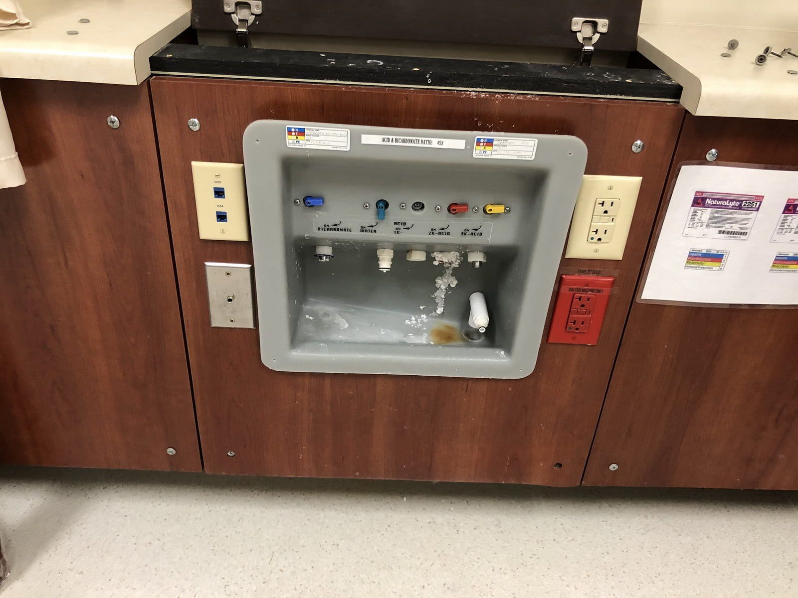 Wall-mounted water fountain with a stainless-steel basin set into a wood-paneled counter.