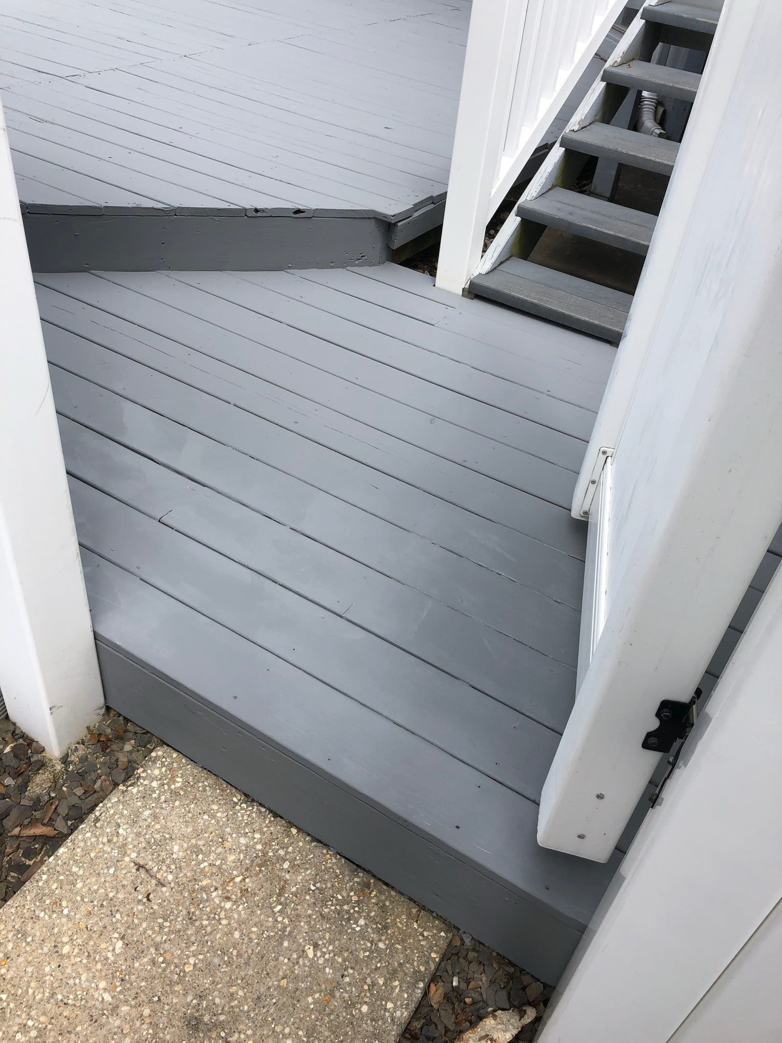 Gray porch landing with open white doors and stairs leading up to a deck.