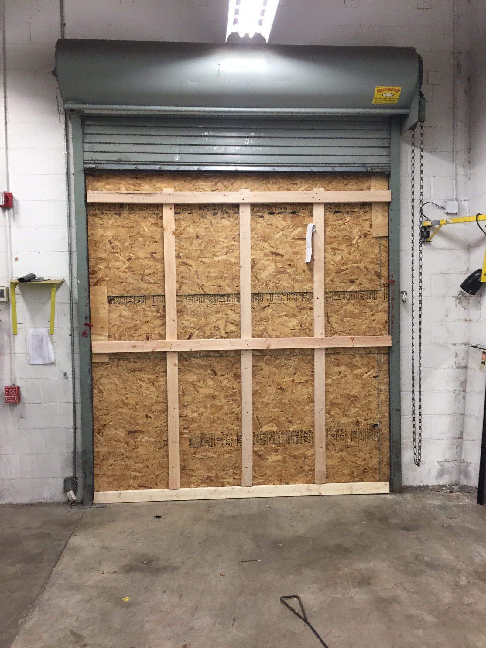 Industrial loading dock with a boarded-up roll-up door in a warehouse.