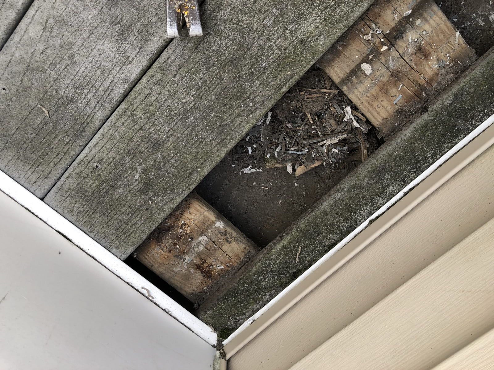 Damaged wooden deck boards with a large hole exposing debris underneath.