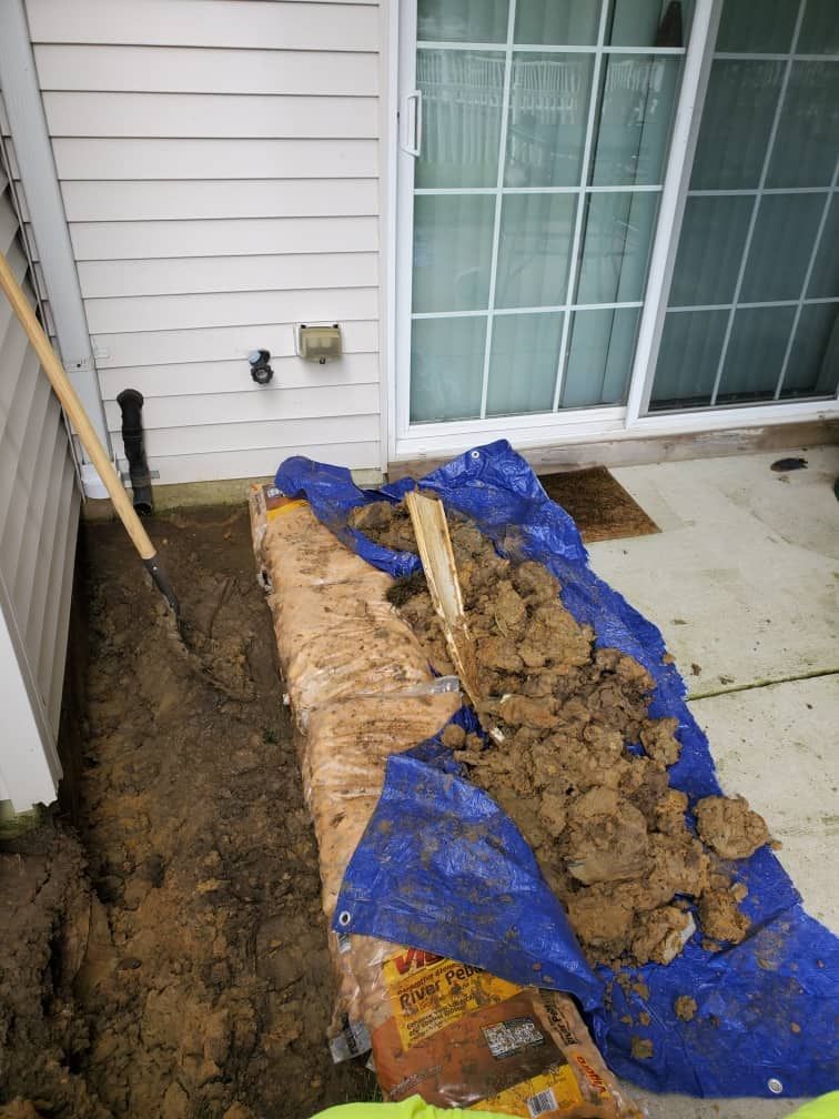 Mud and dirt piled on a blue tarp beside a house wall and sliding glass door.