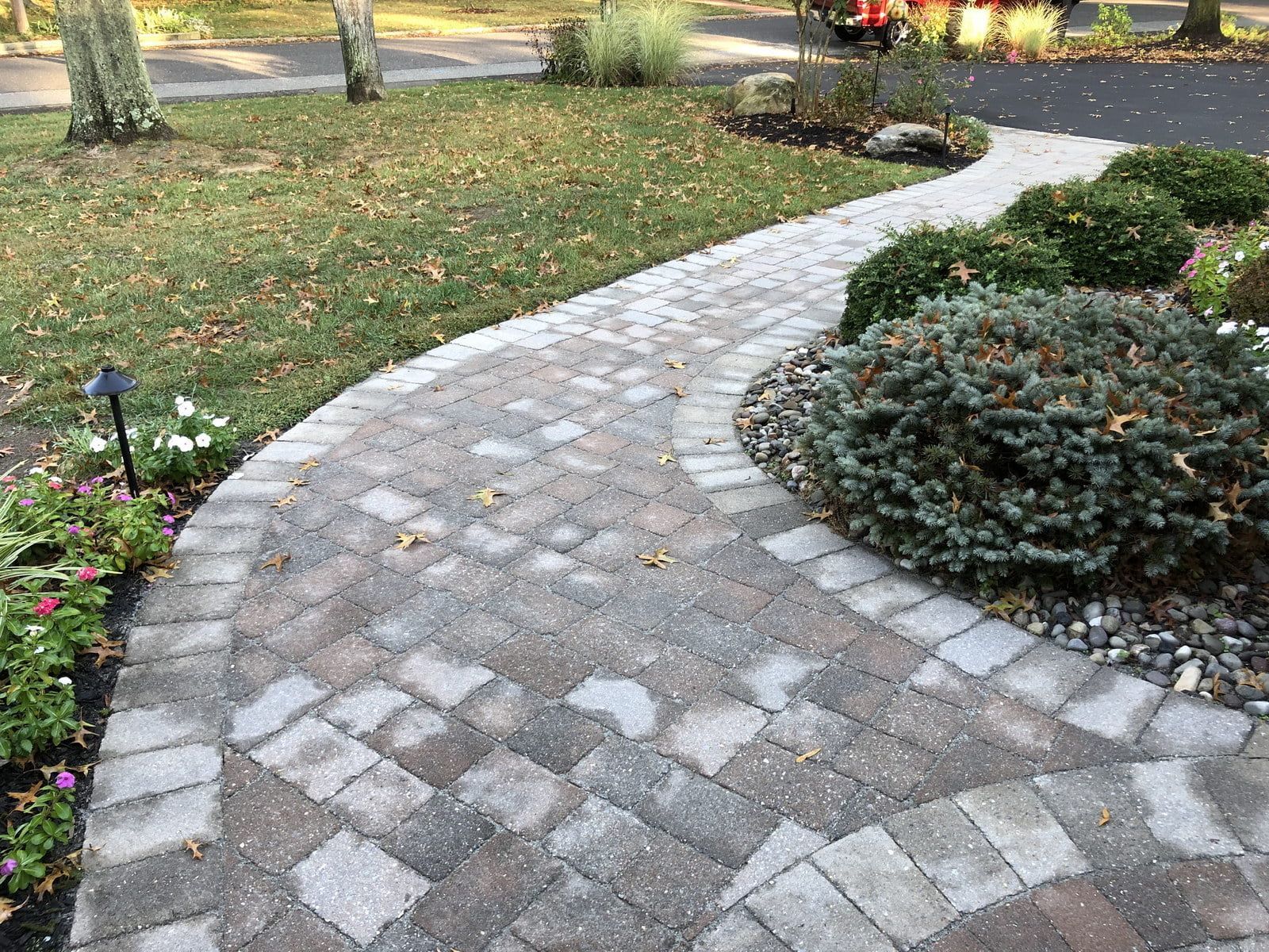 Curved stone garden path through a landscaped yard with shrubs and flowers