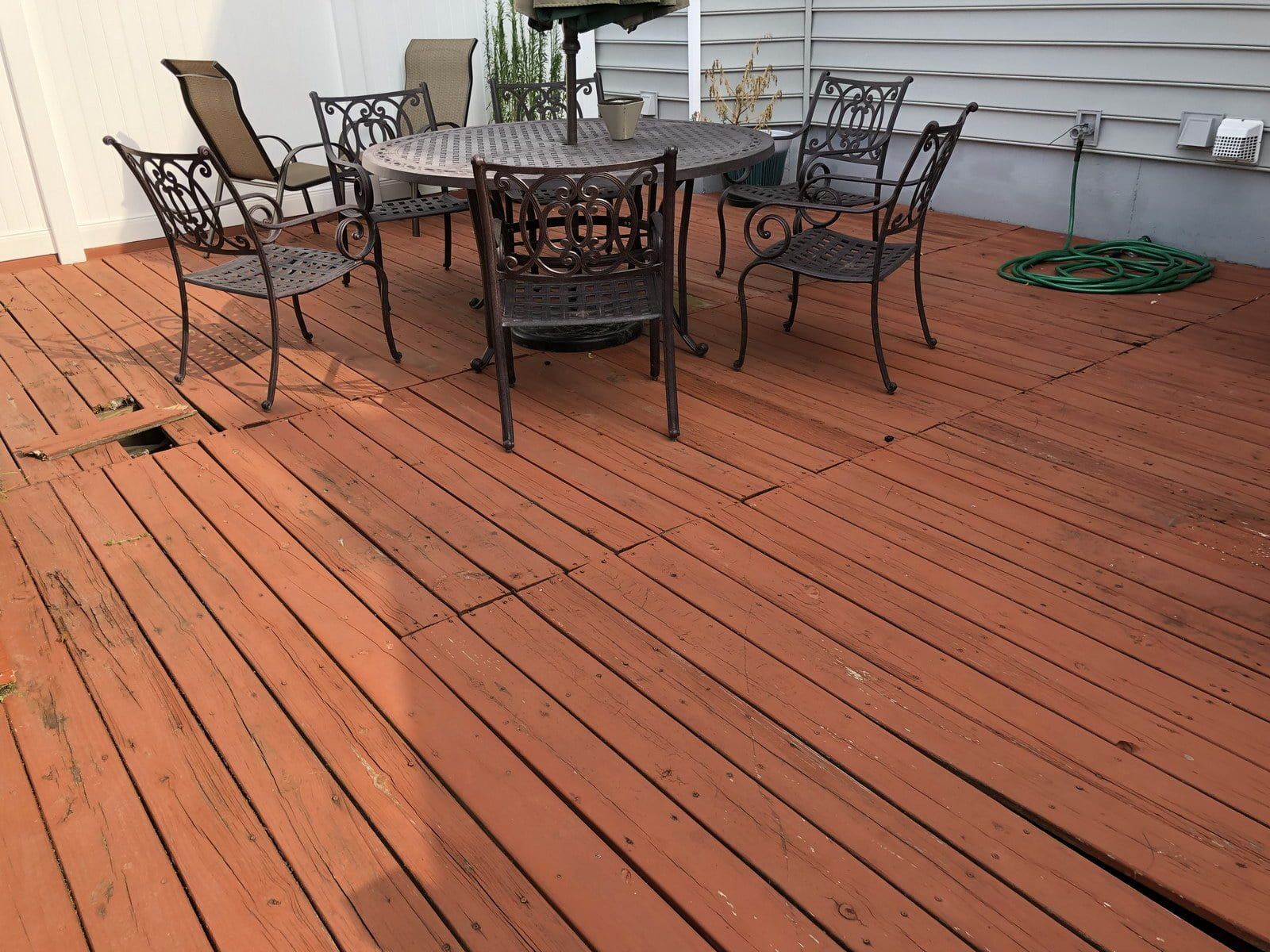 Wooden deck with metal patio table and chairs beside a house exterior