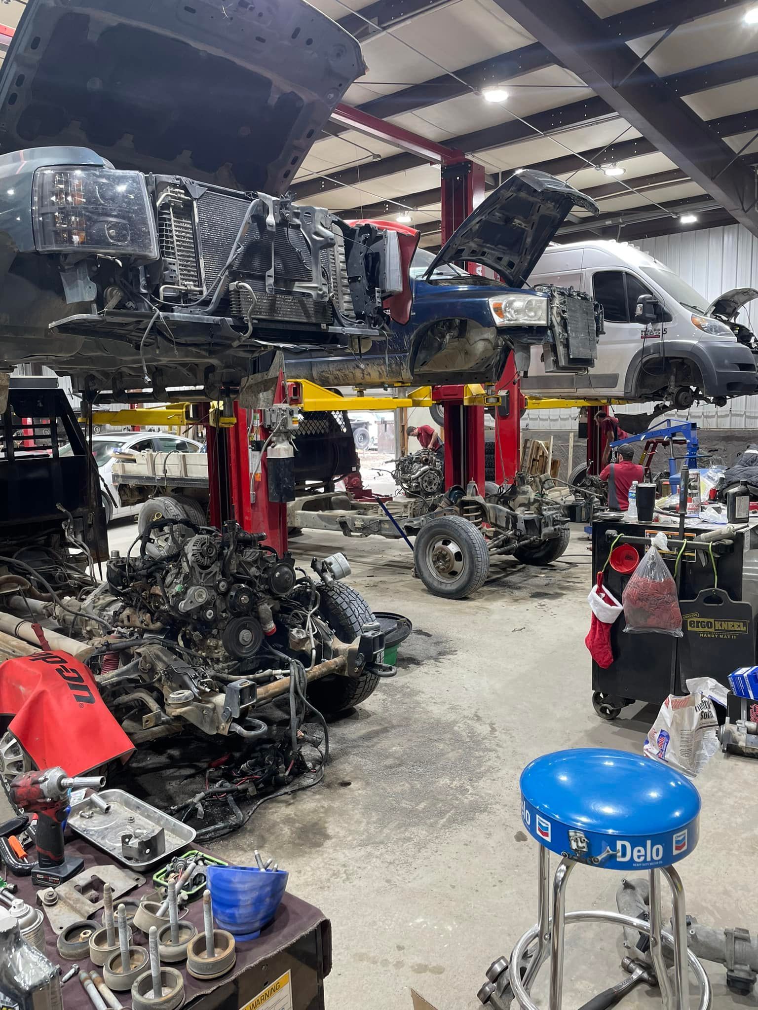 A garage filled with lots of cars and trucks being worked on.