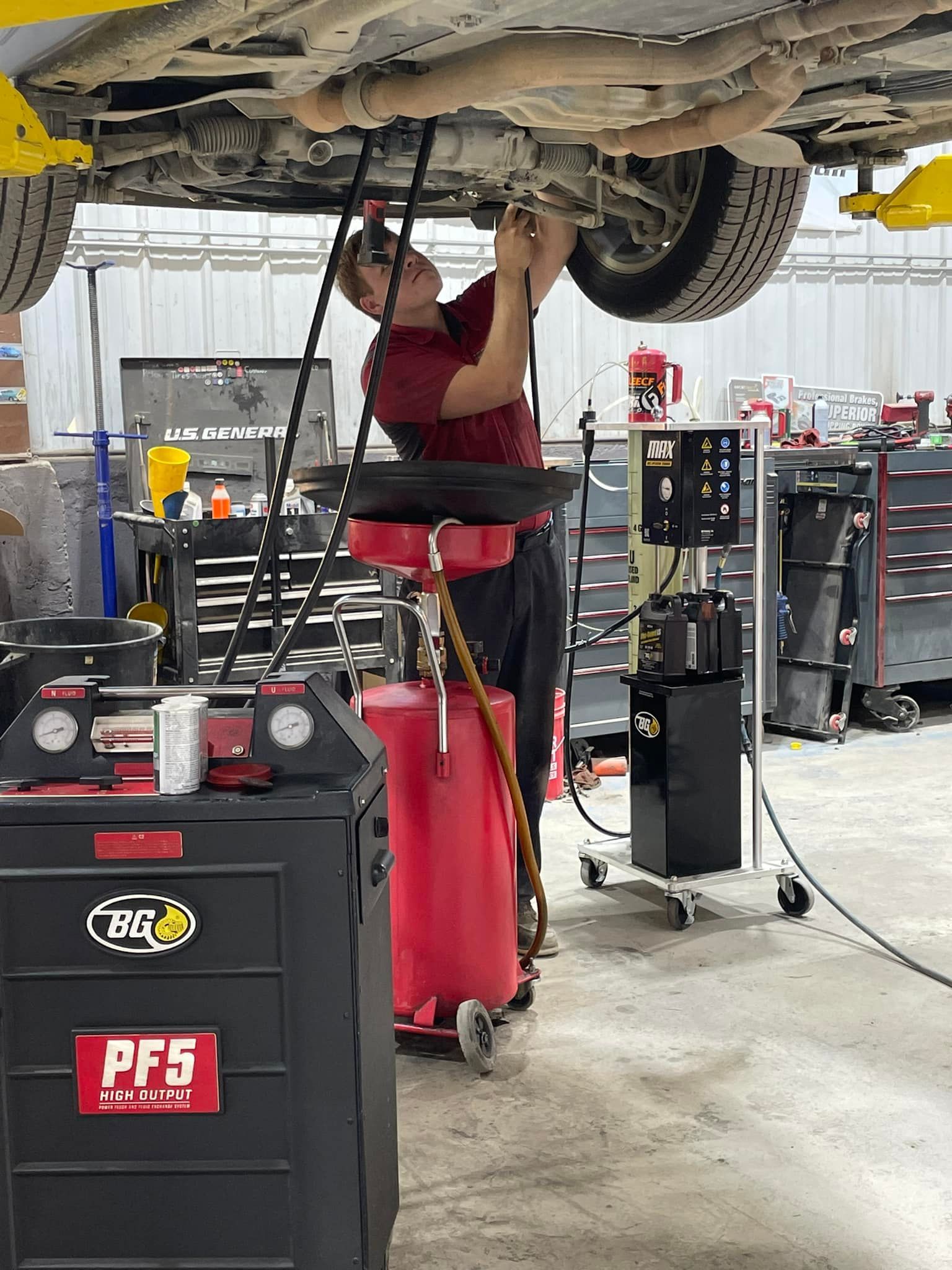 A man is working under a car in a garage.