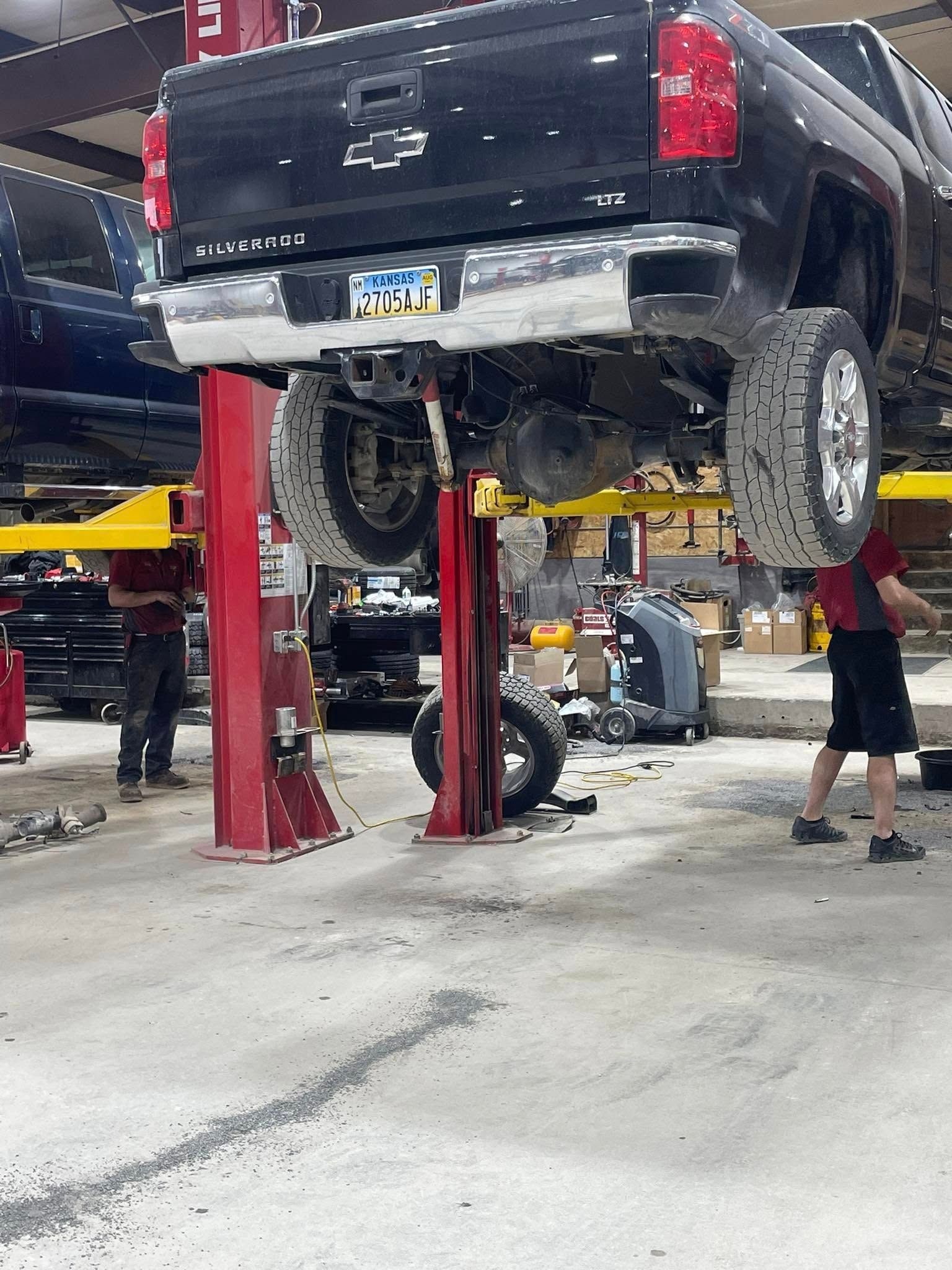 A truck is sitting on a lift in a garage.