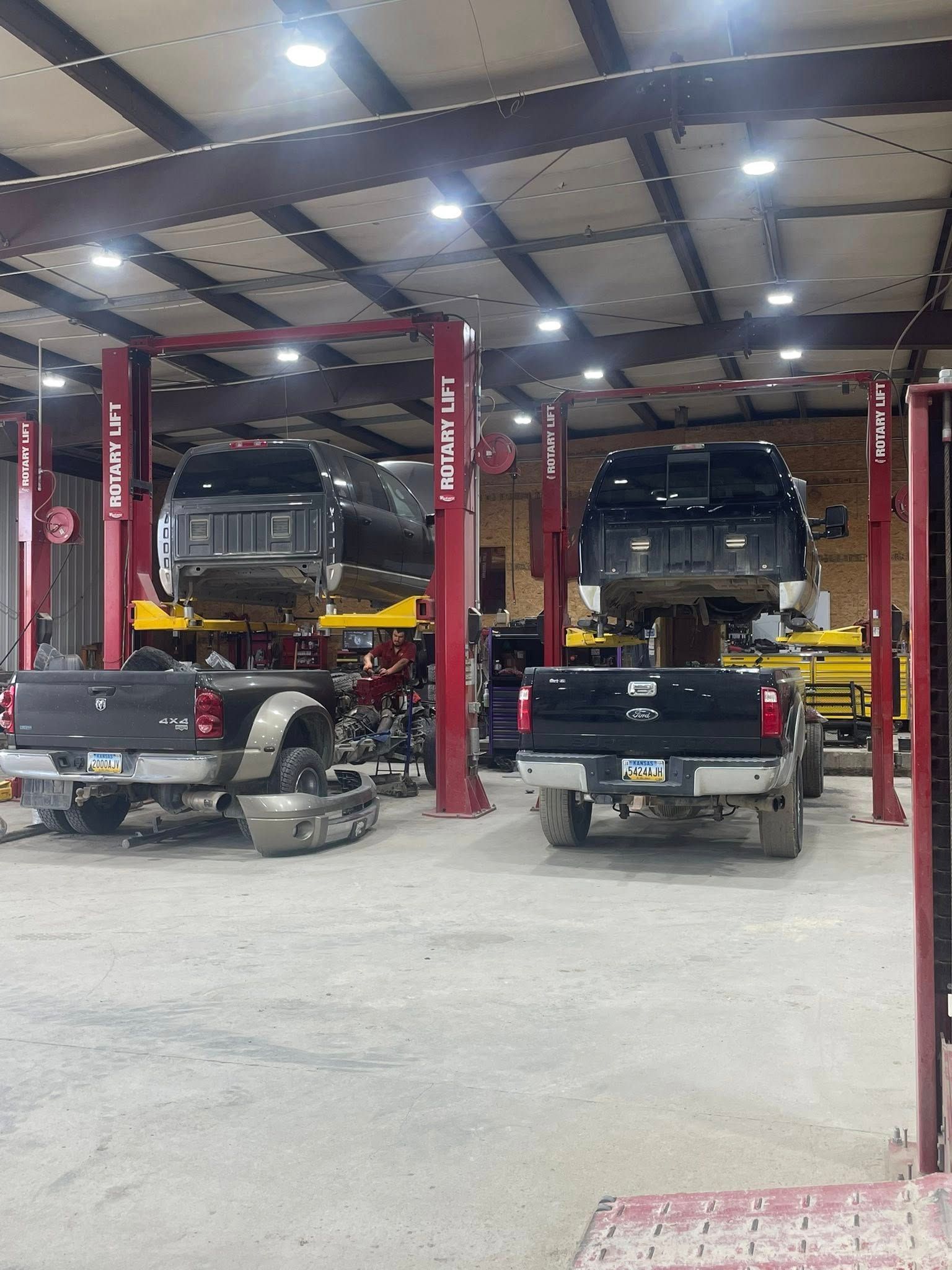 Two trucks are sitting on lifts in a garage.