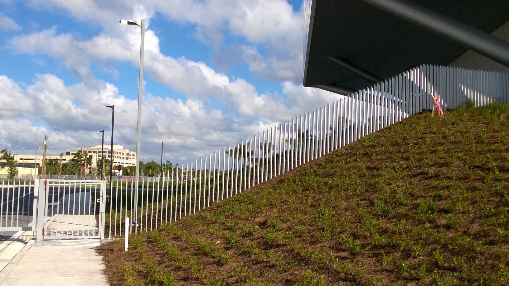 a fence surrounds a grassy hill with a building in the background .