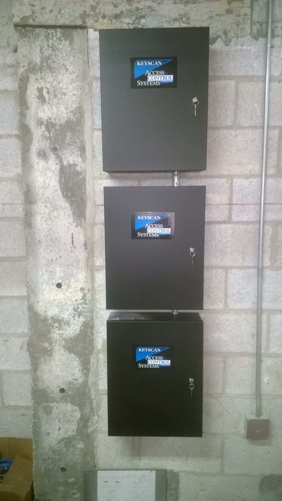 three black boxes are stacked on top of each other on a brick wall .