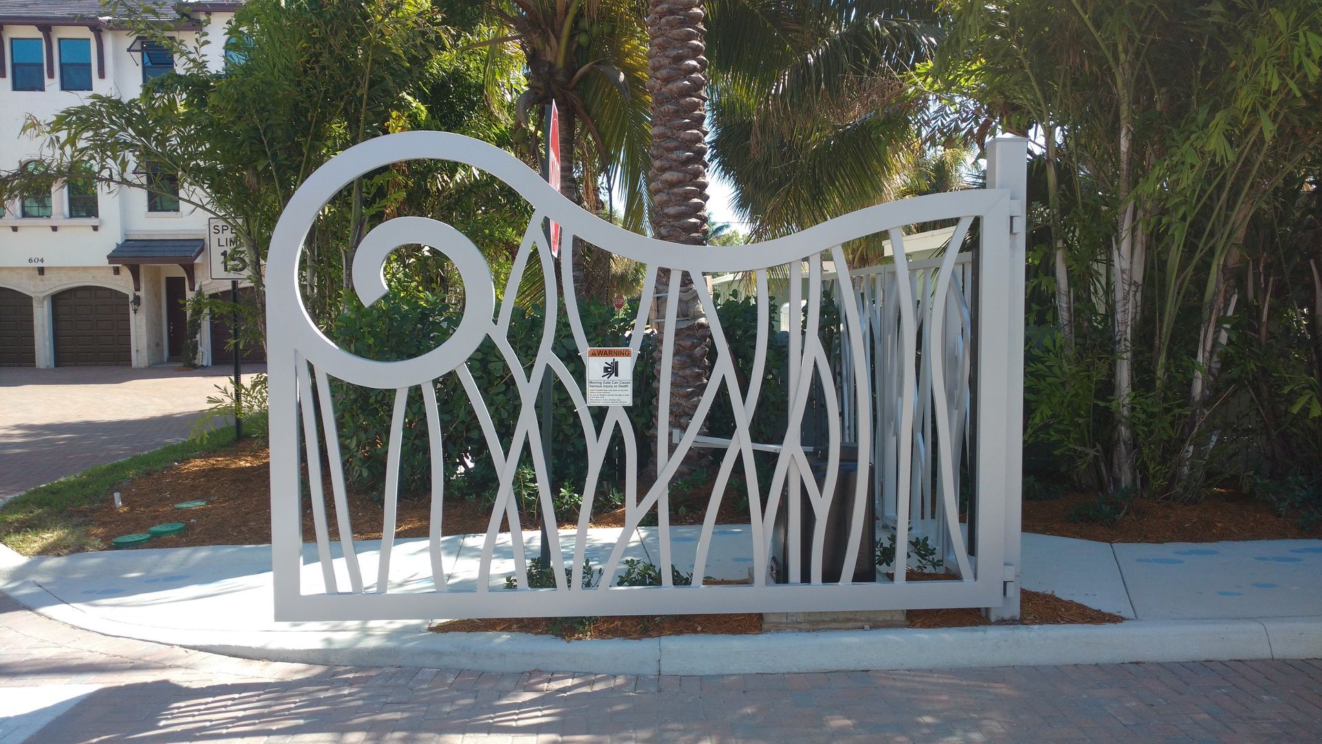 a white gate with a swirl design is in front of a house .