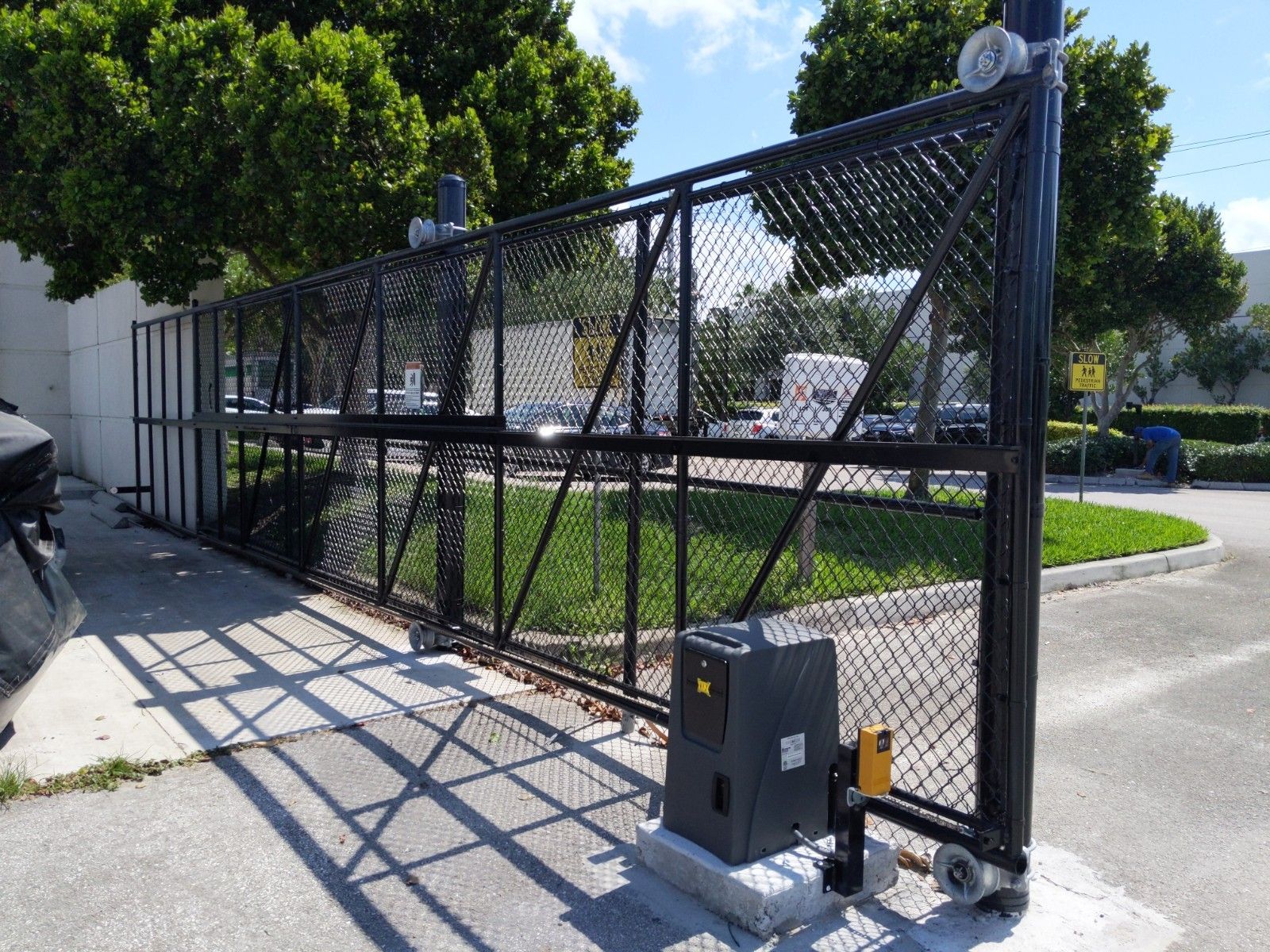 a black chain link fence with a sliding gate in front of a building .
