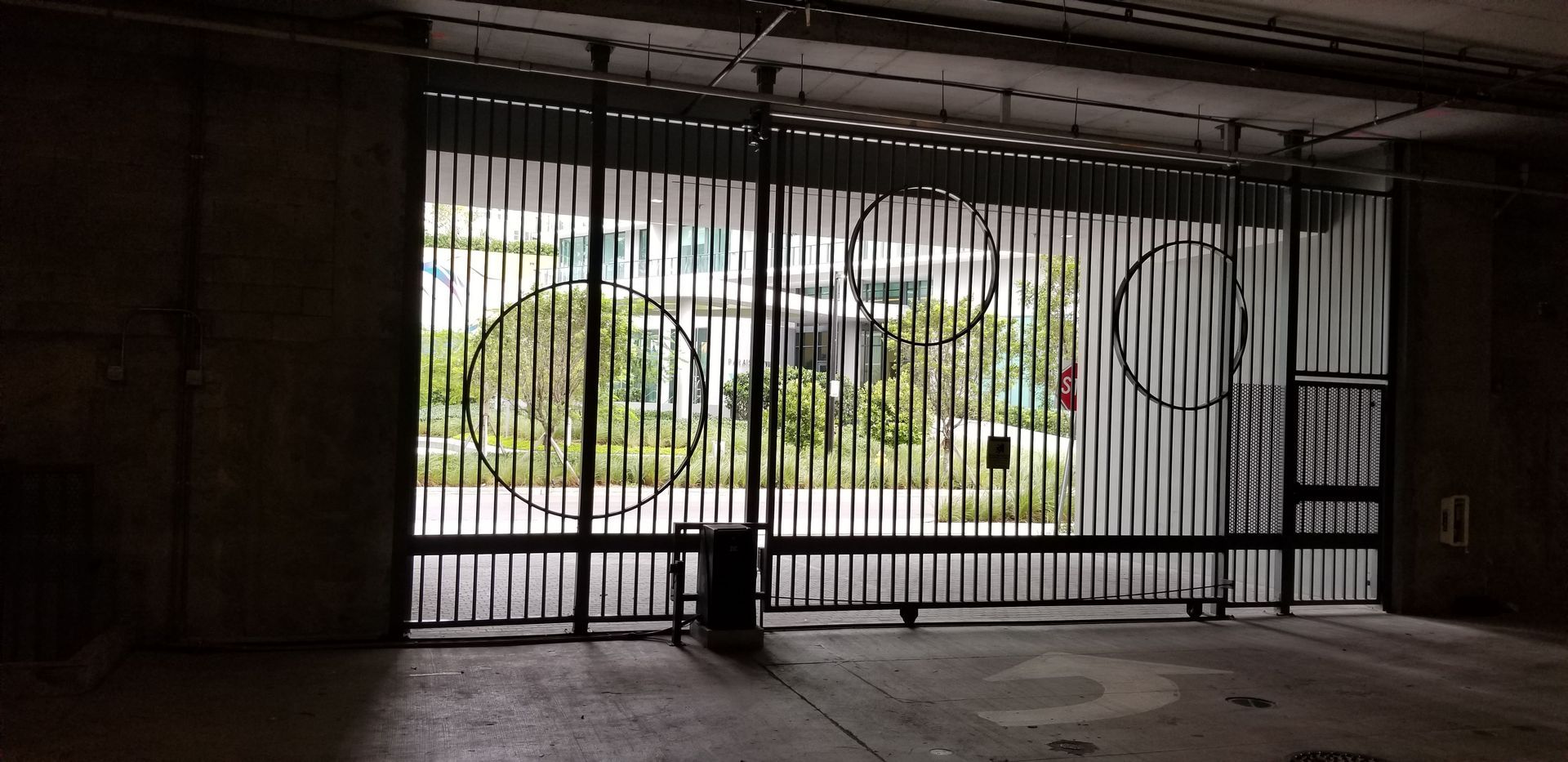 an empty garage with a fence and graffiti on the wall .