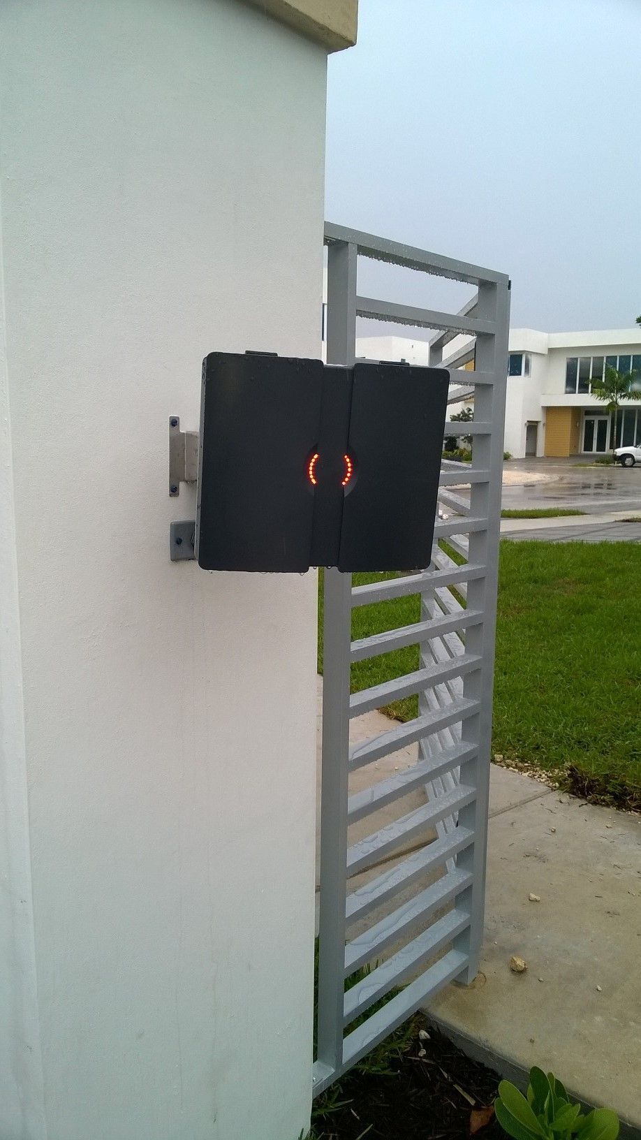 a black box is attached to a white wall next to a gate .