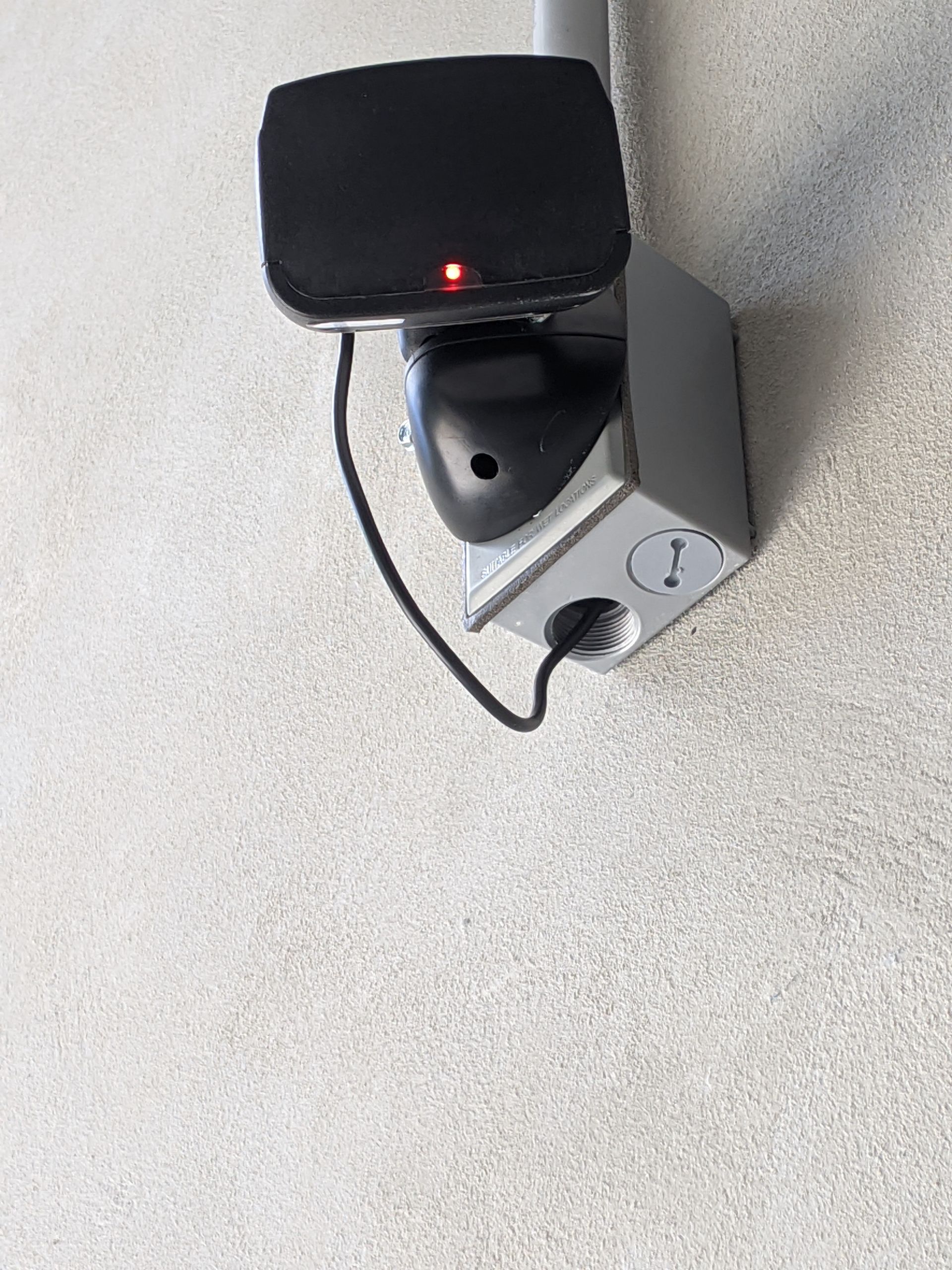 a black device with a red light on it is plugged into a power outlet .