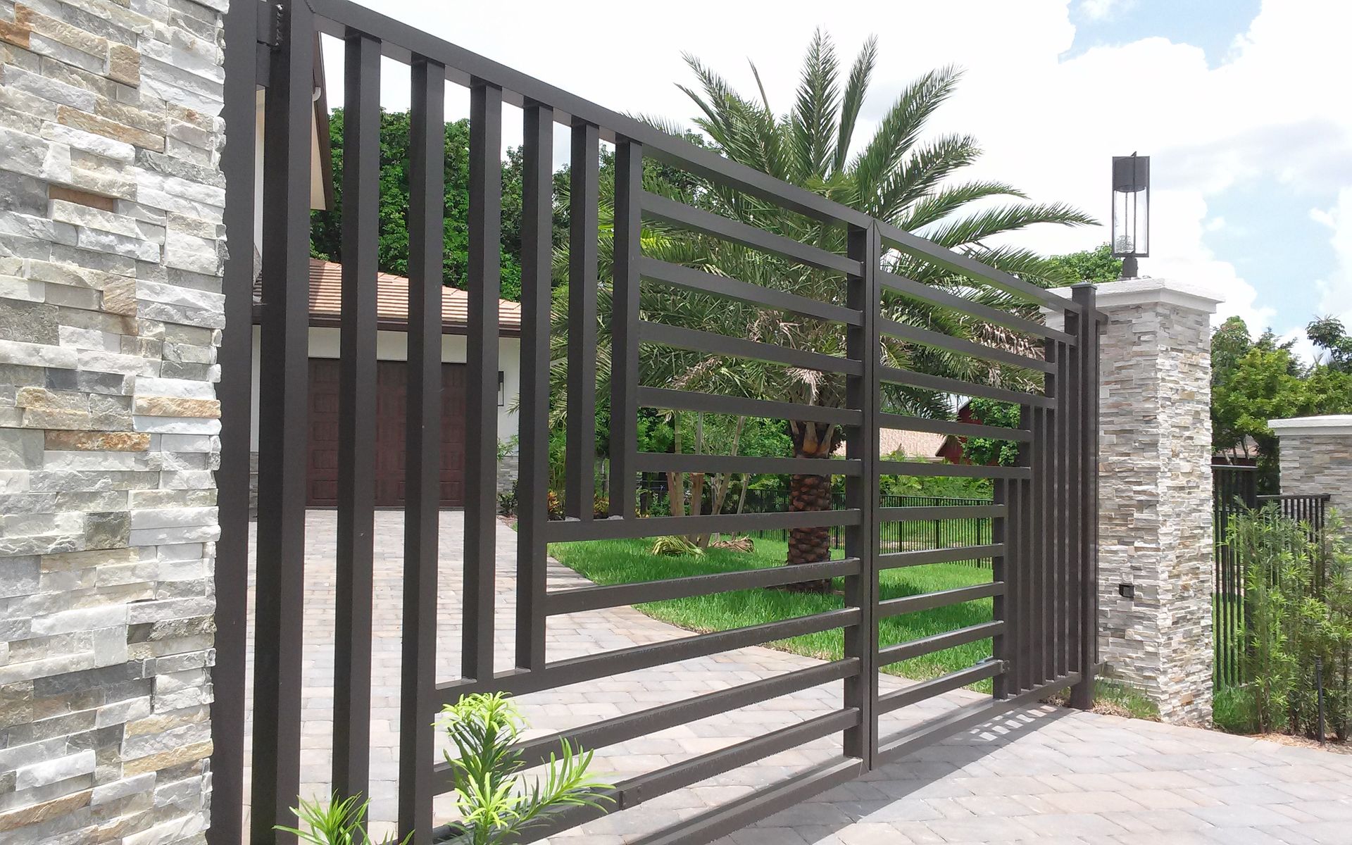 a sliding gate is open to a driveway with a palm tree in the background .