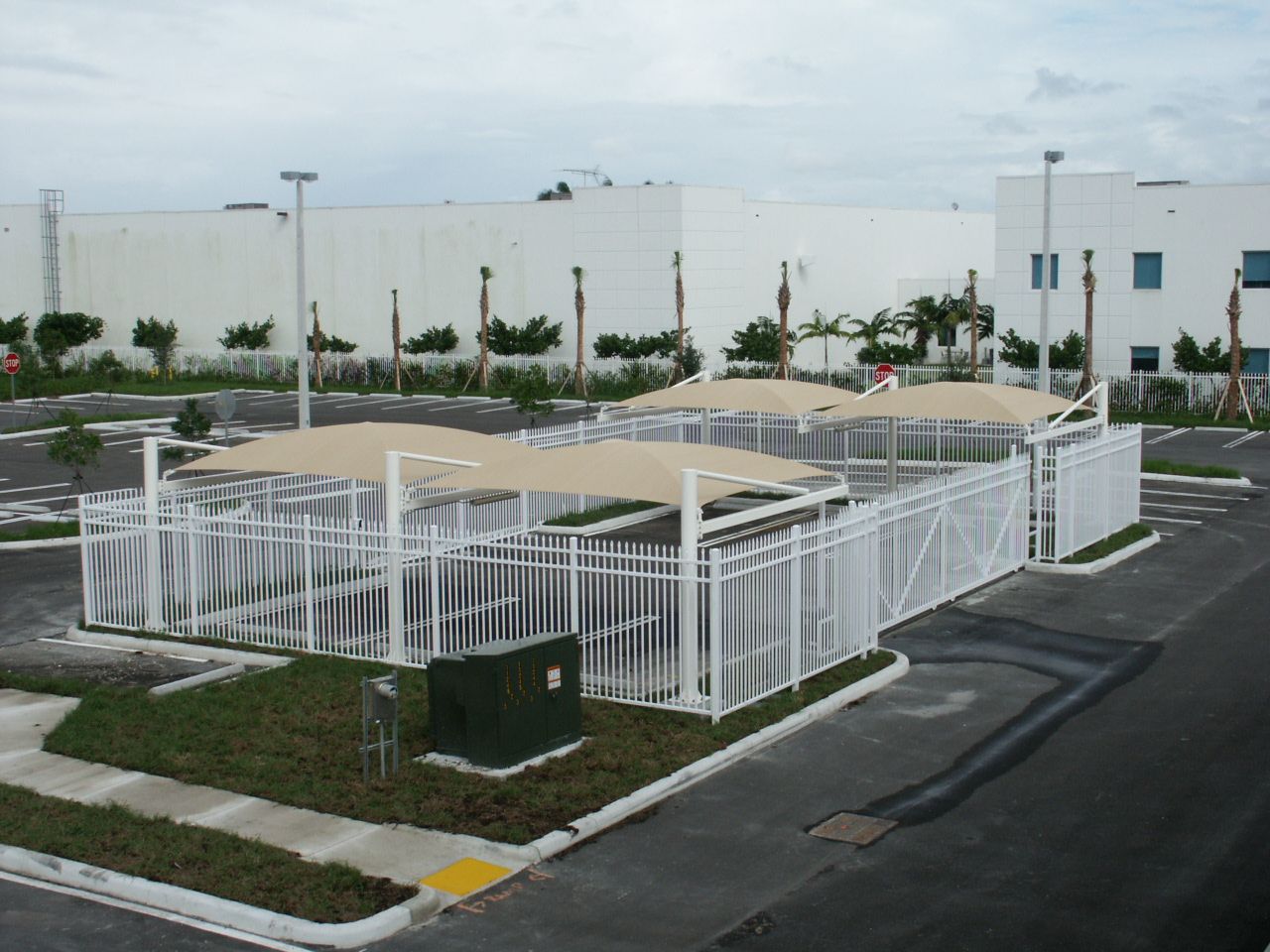 an aerial view of a parking lot with shades and a white fence