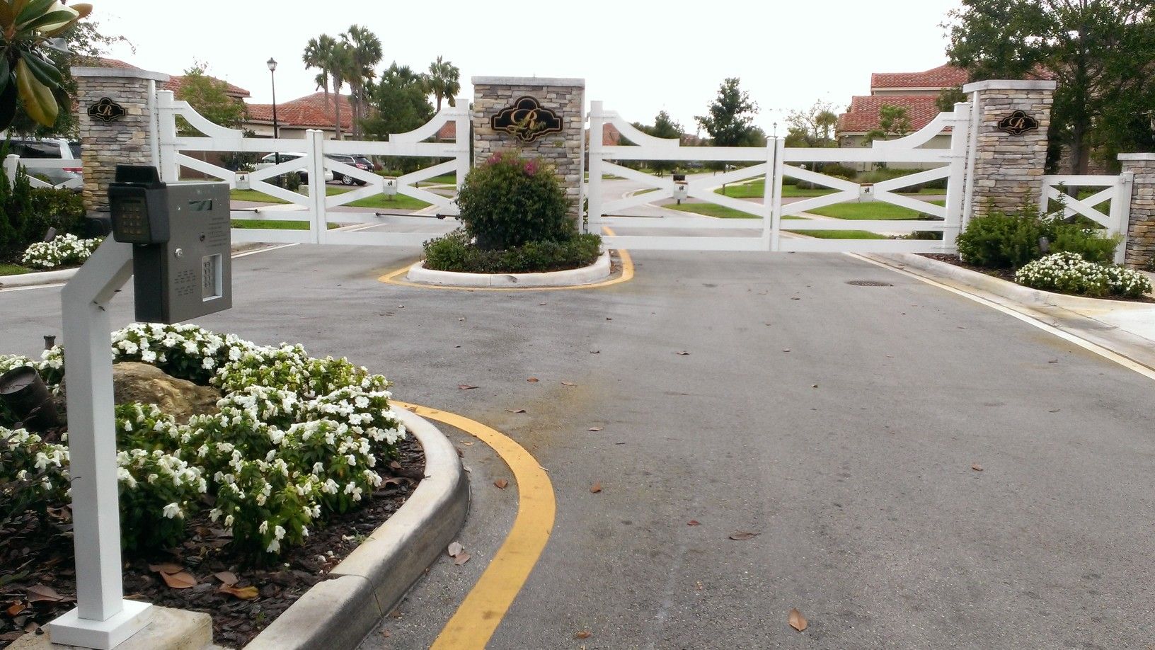 a driveway with a white gate and a mailbox