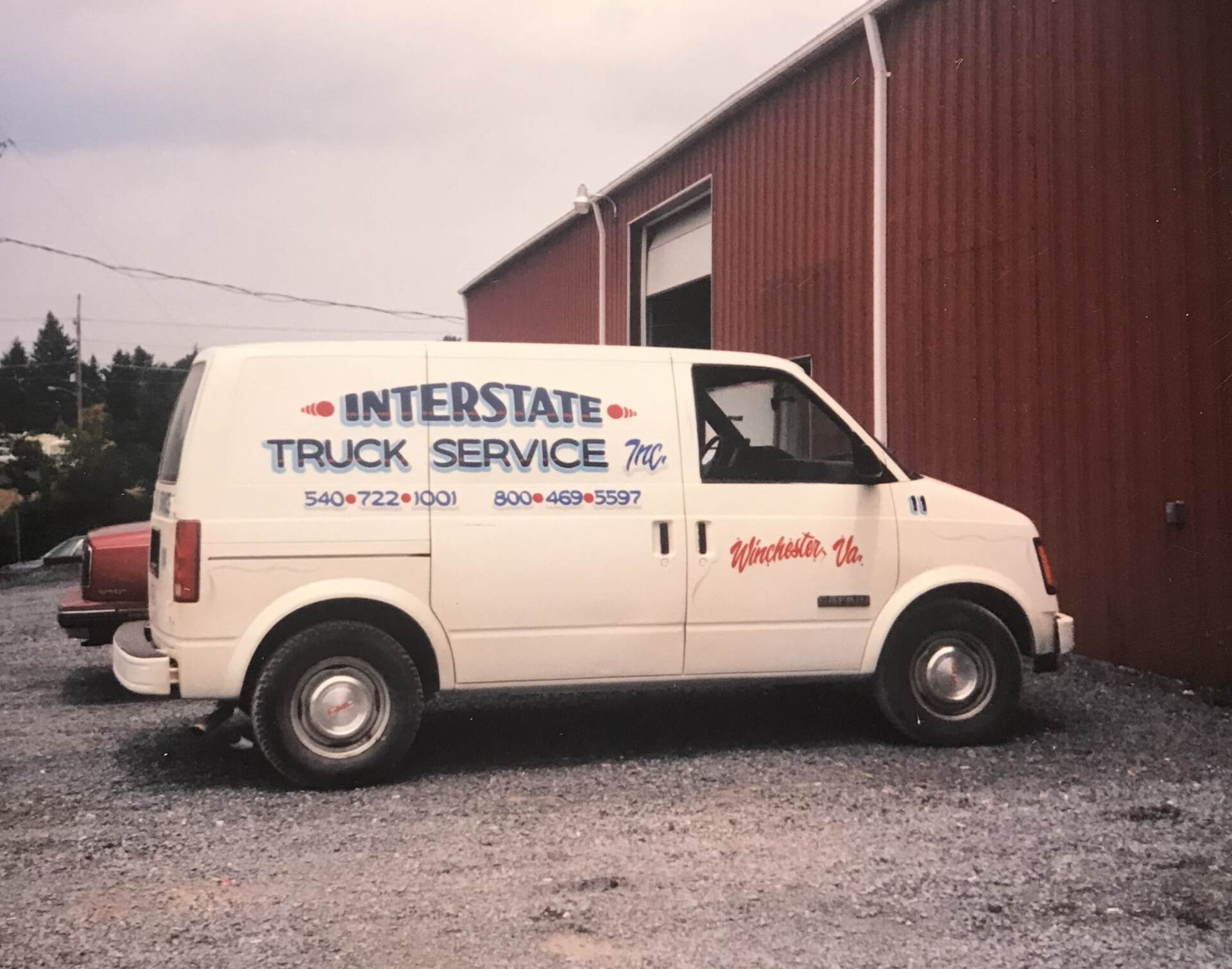 White van parked in front of a red building, with