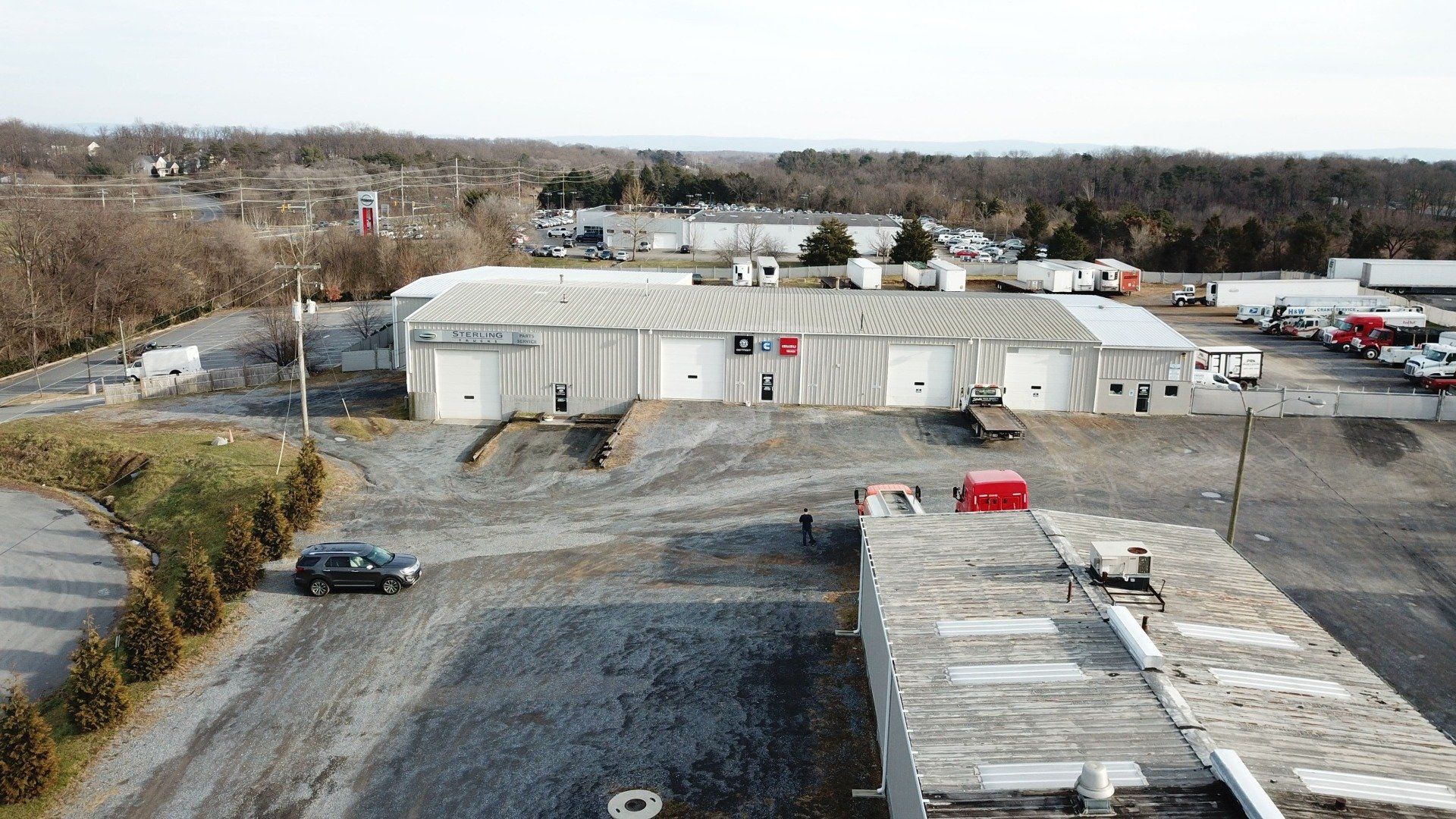 Aerial view of a commercial building with multiple garage doors, a flagpole, and surrounding parking lot.