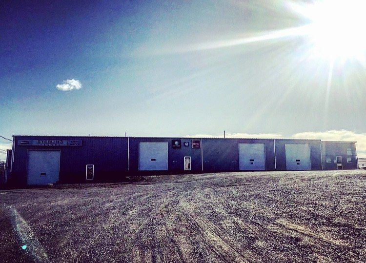 Metal building with multiple garage doors under a bright sun.