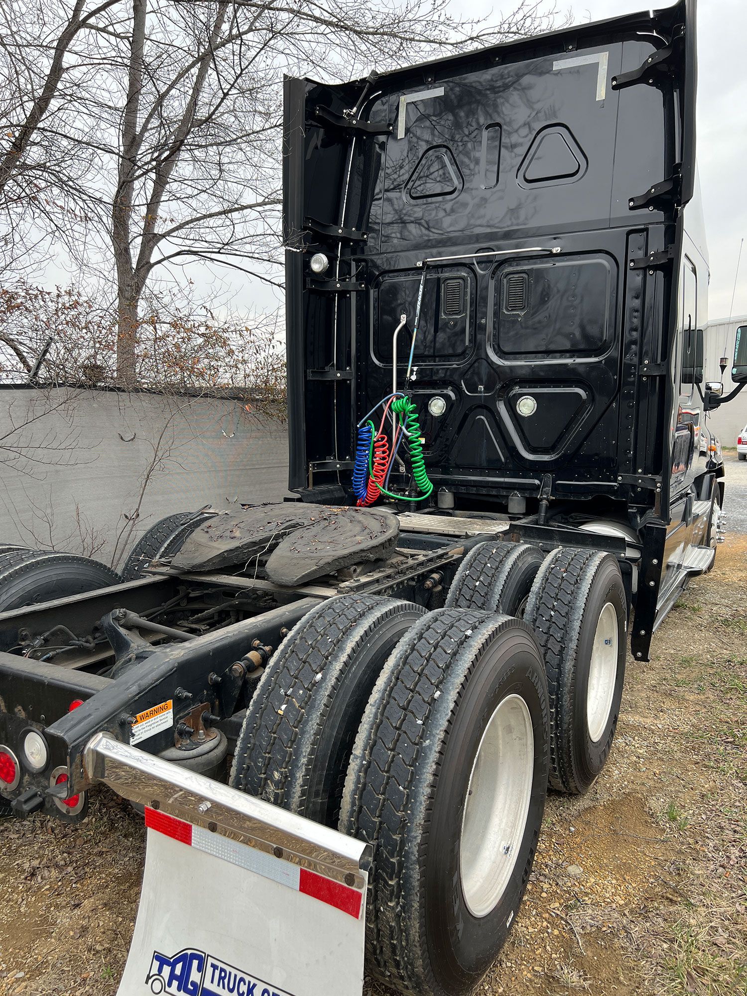 A black semi truck is parked on the side of the road 