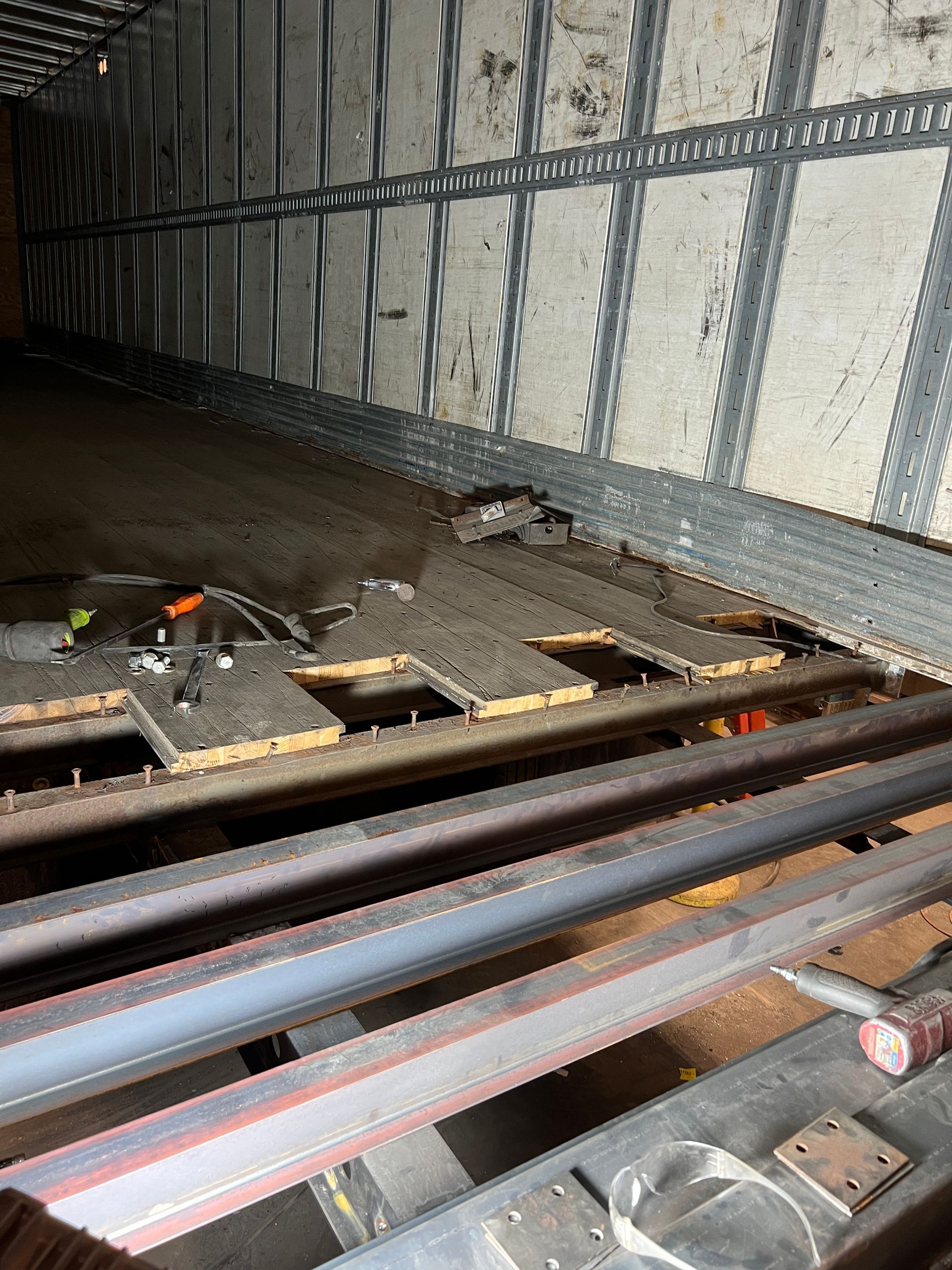 The inside of a truck with a broken floor and a ladder.