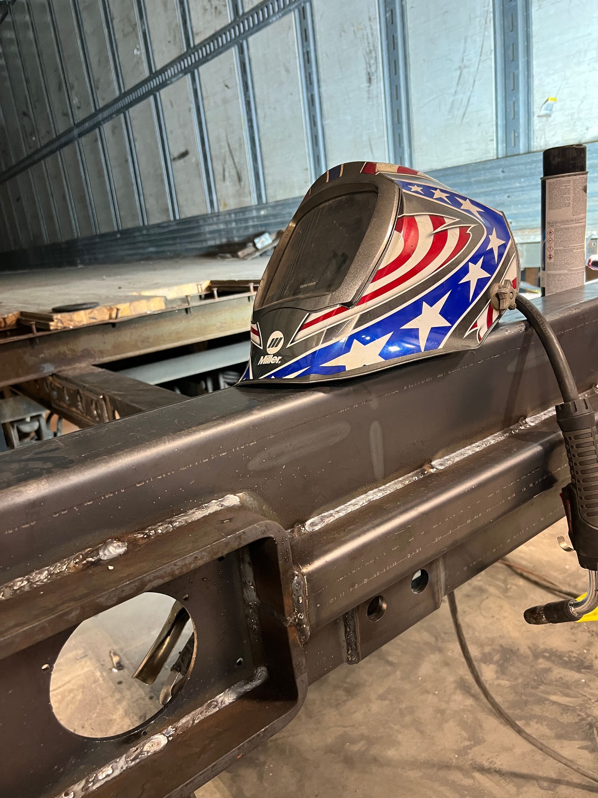 A welding helmet is sitting on top of a metal beam.