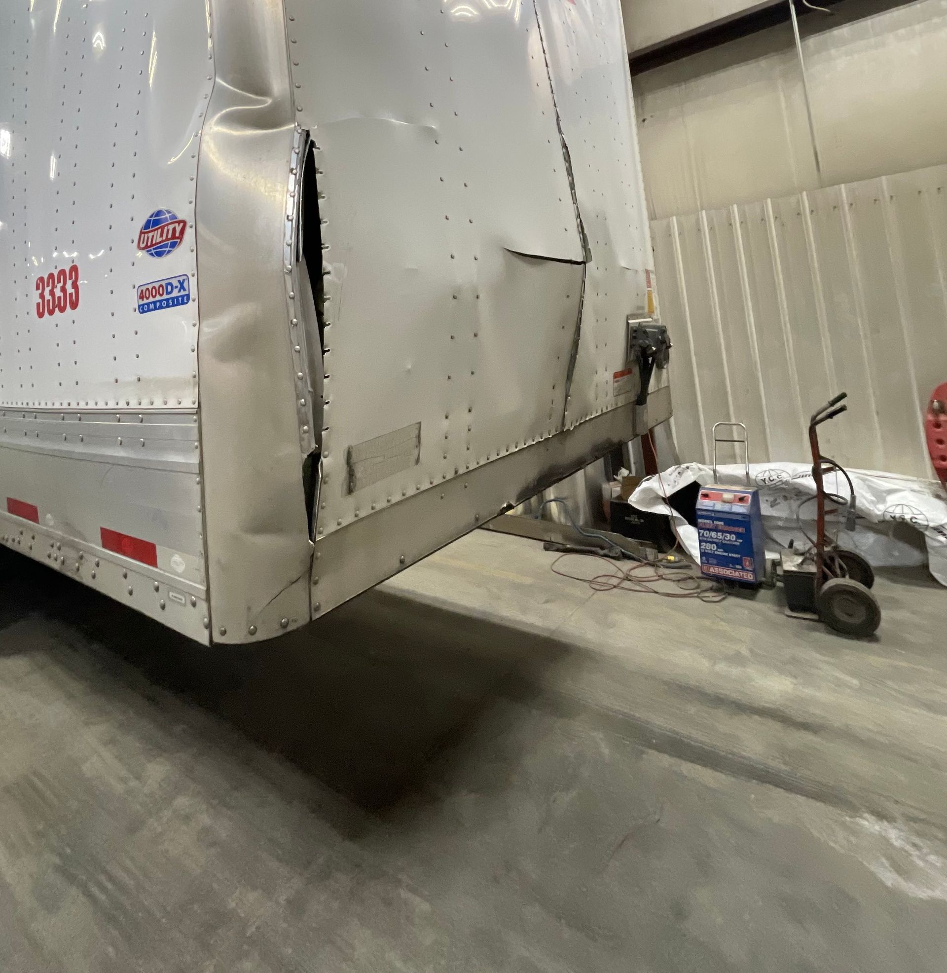 A white truck with a damaged side is parked in a garage.