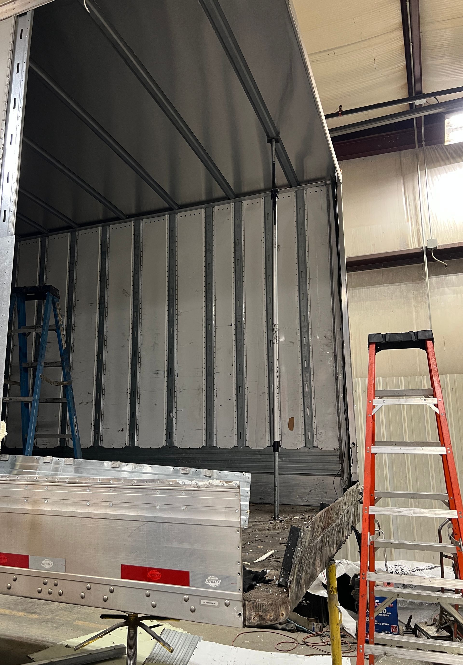 A truck is being repaired in a garage with a ladder.