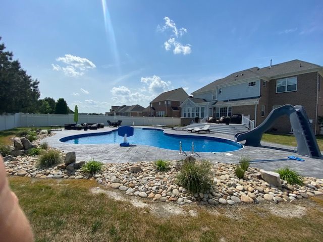 A large swimming pool with a slide in the backyard of a house.