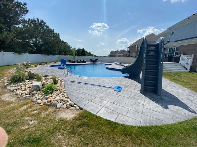 A swimming pool with a slide in the backyard of a house.