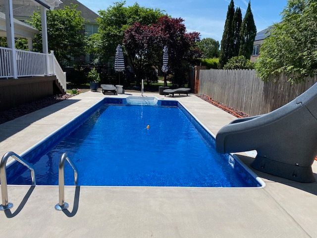 A large swimming pool with a slide in the backyard