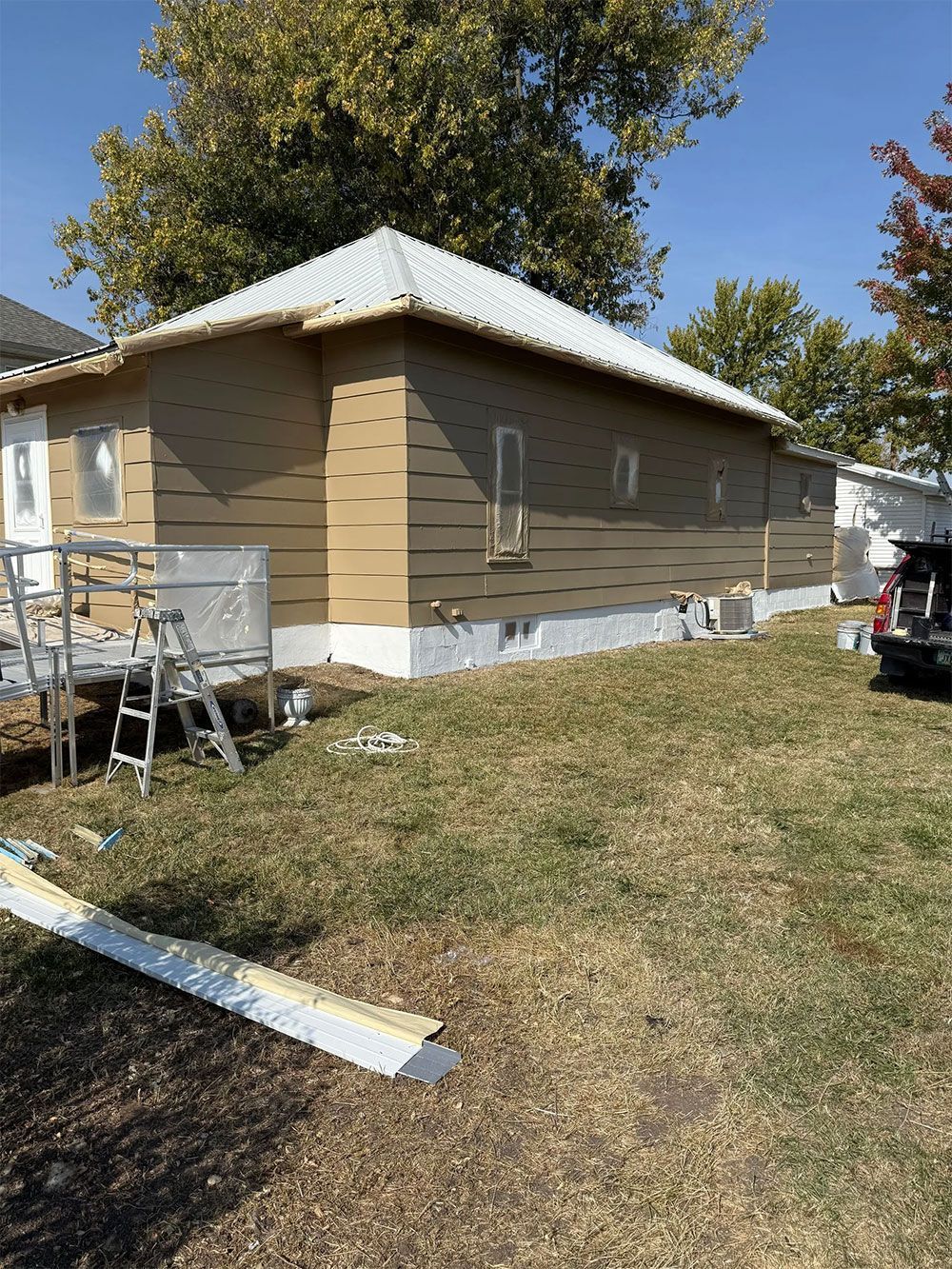 House exterior under construction, with exposed siding, a white foundation, and building materials on the lawn.