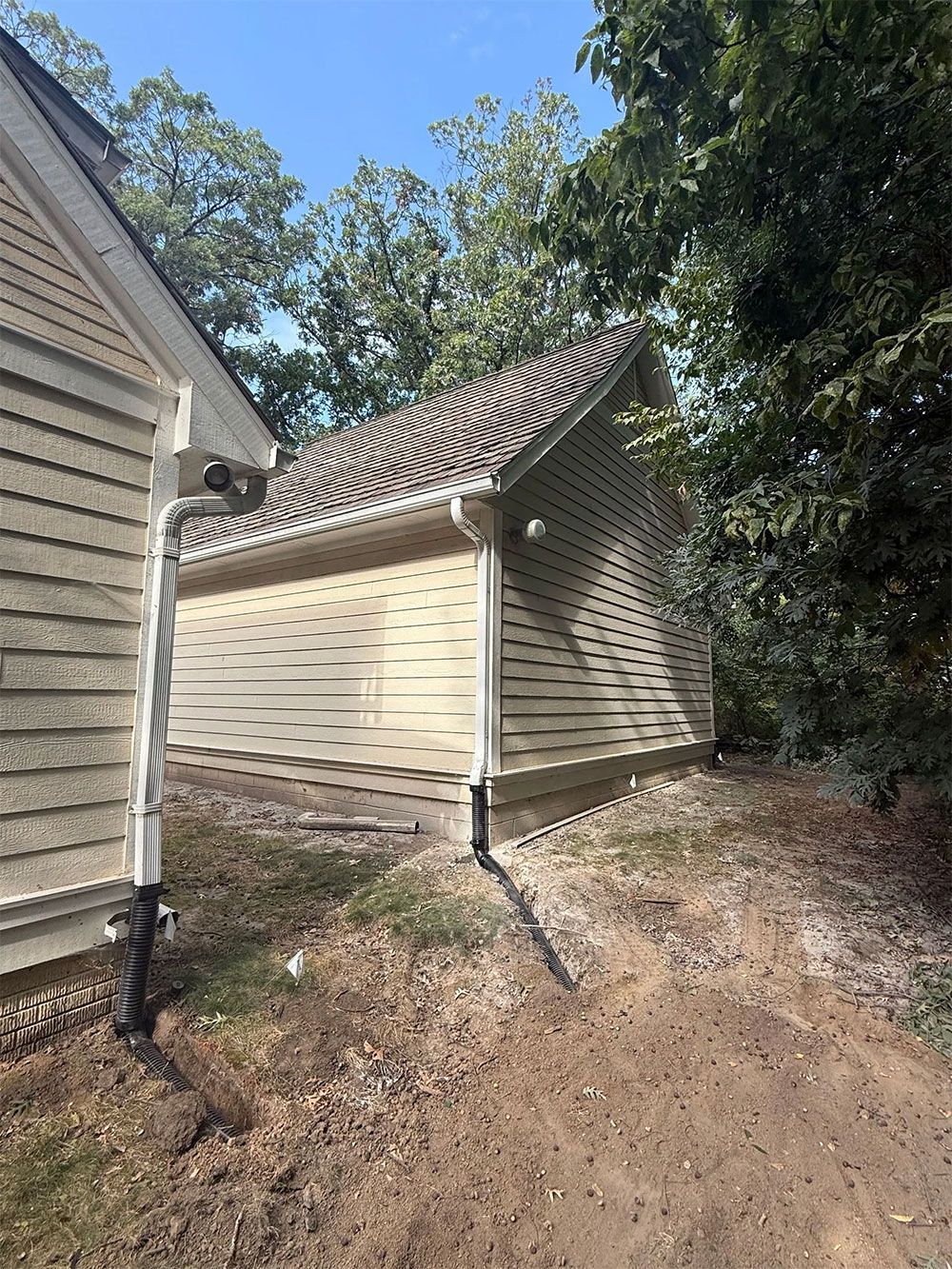Exterior view of a beige building with a gabled roof and surrounding trees.