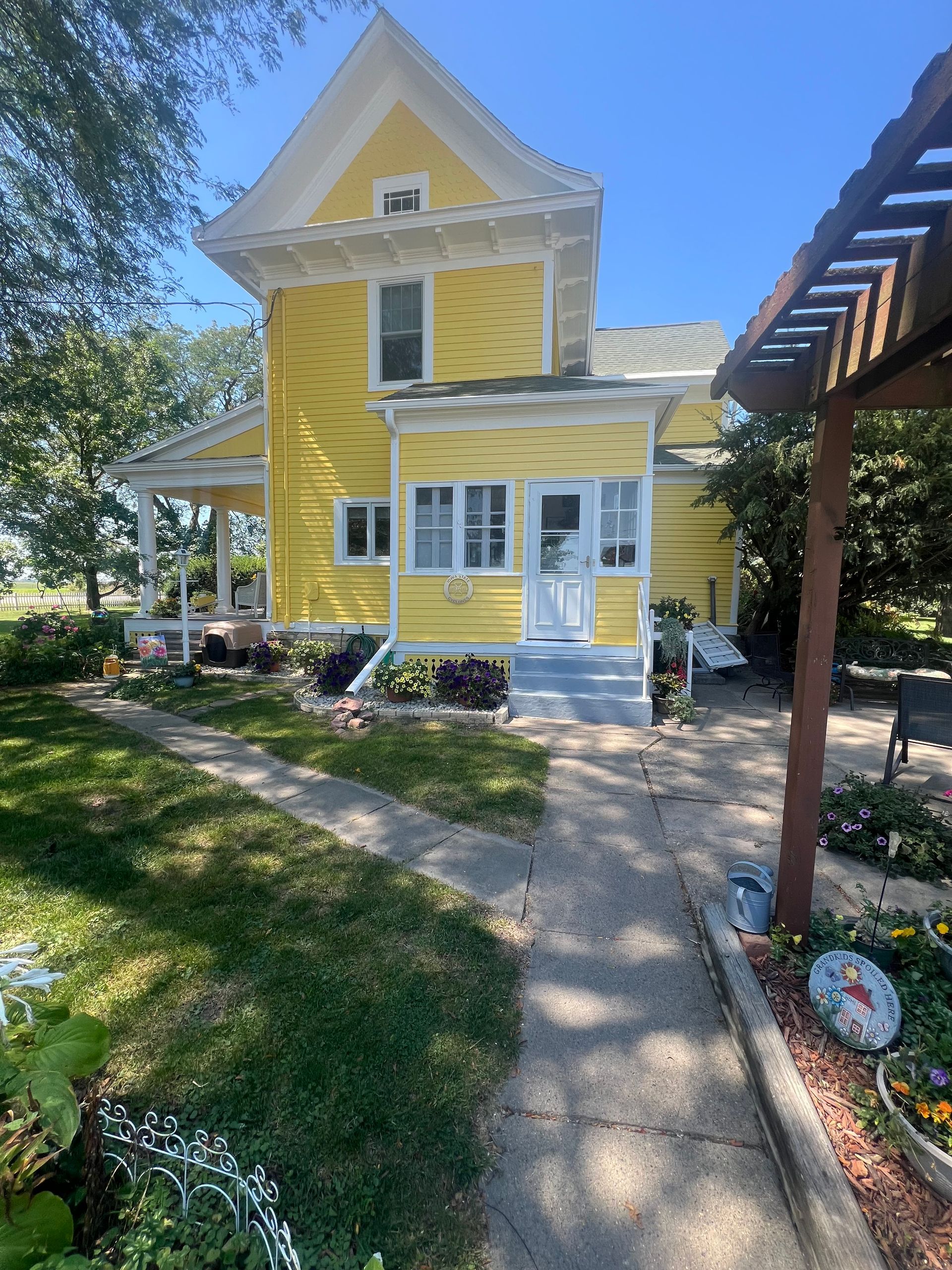 Yellow house with a porch and a walkway, sunny day.