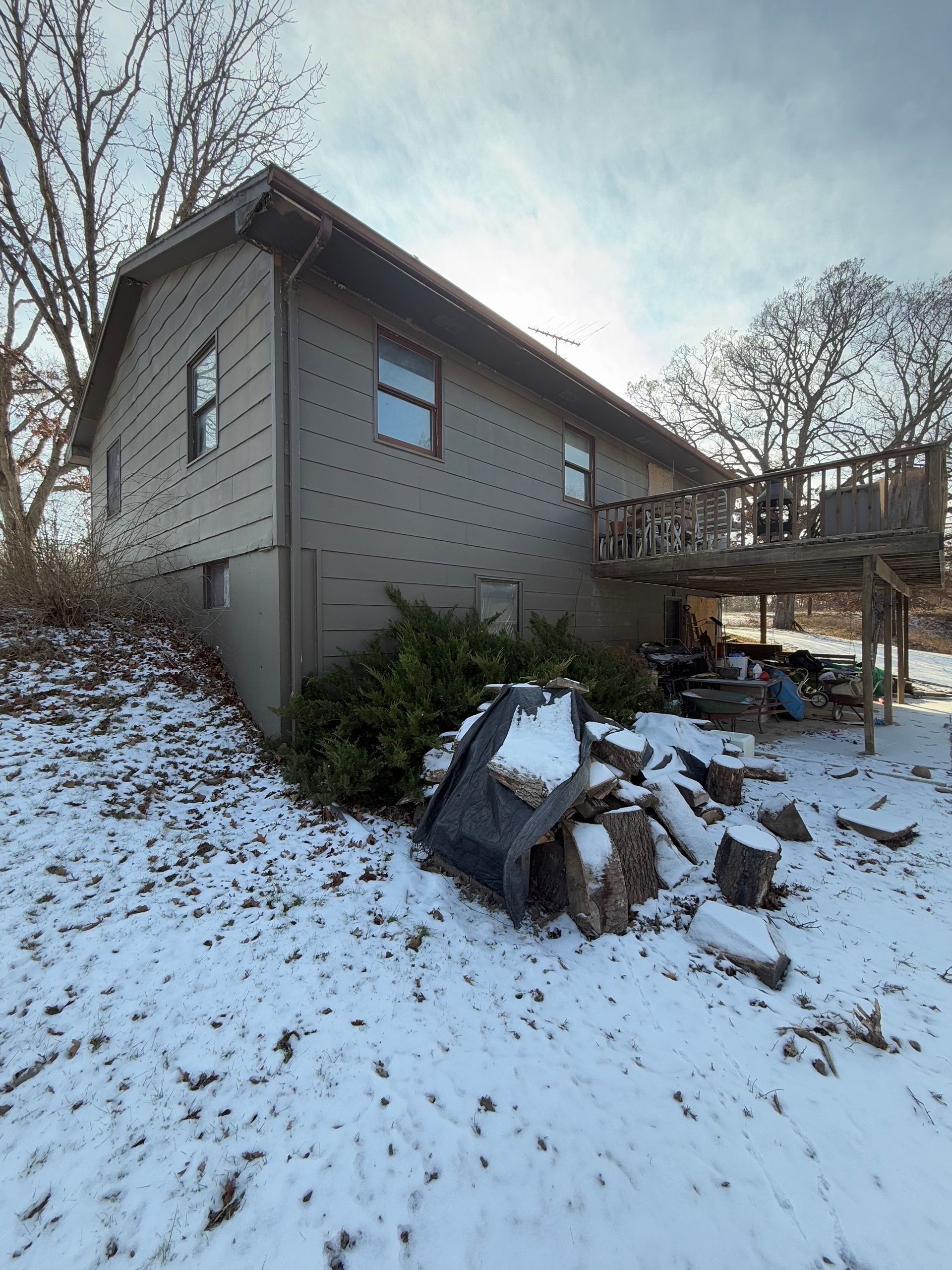 Two-story house with a deck in a snowy setting.