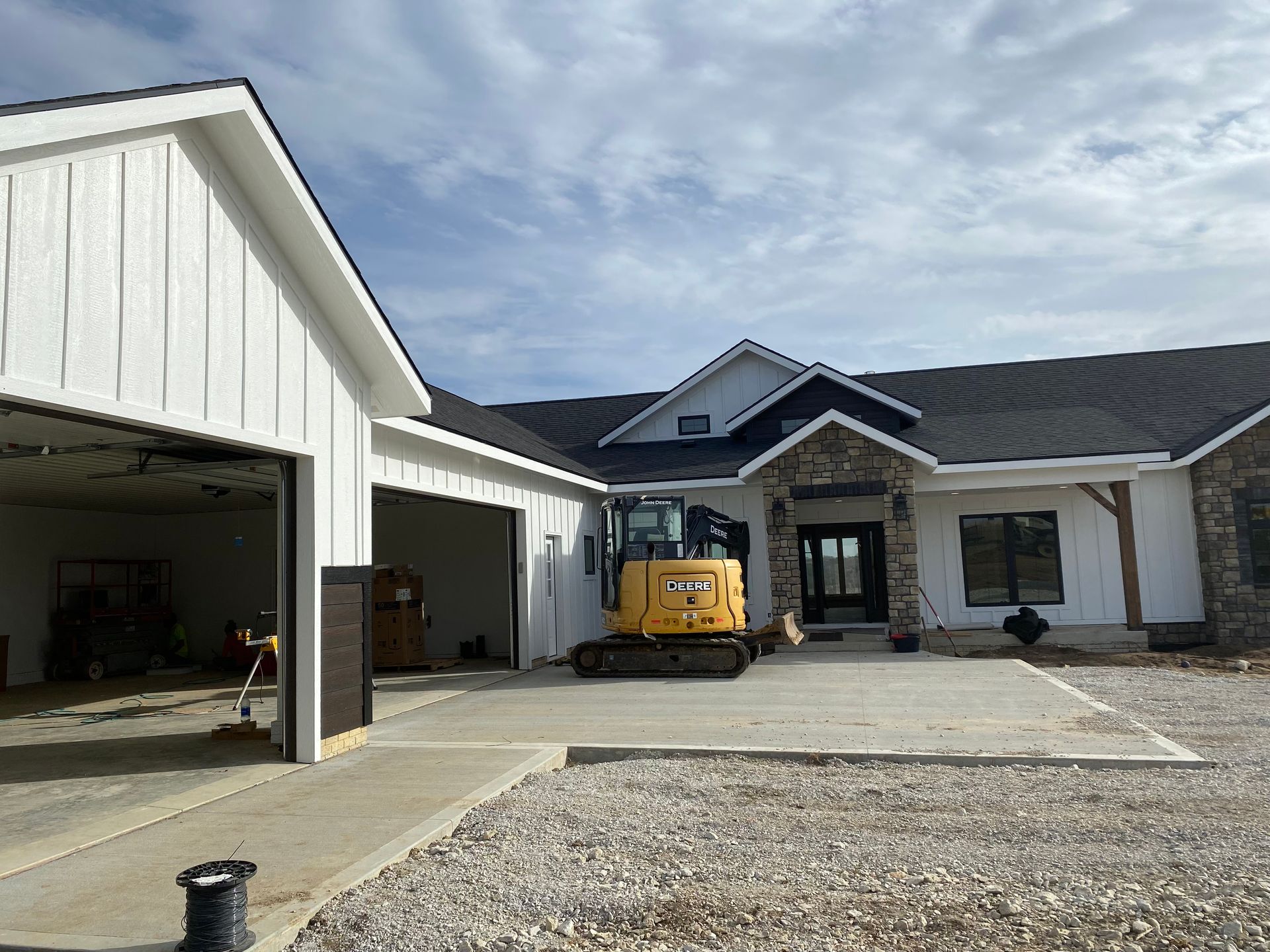 New home under construction with yellow excavator parked in front.