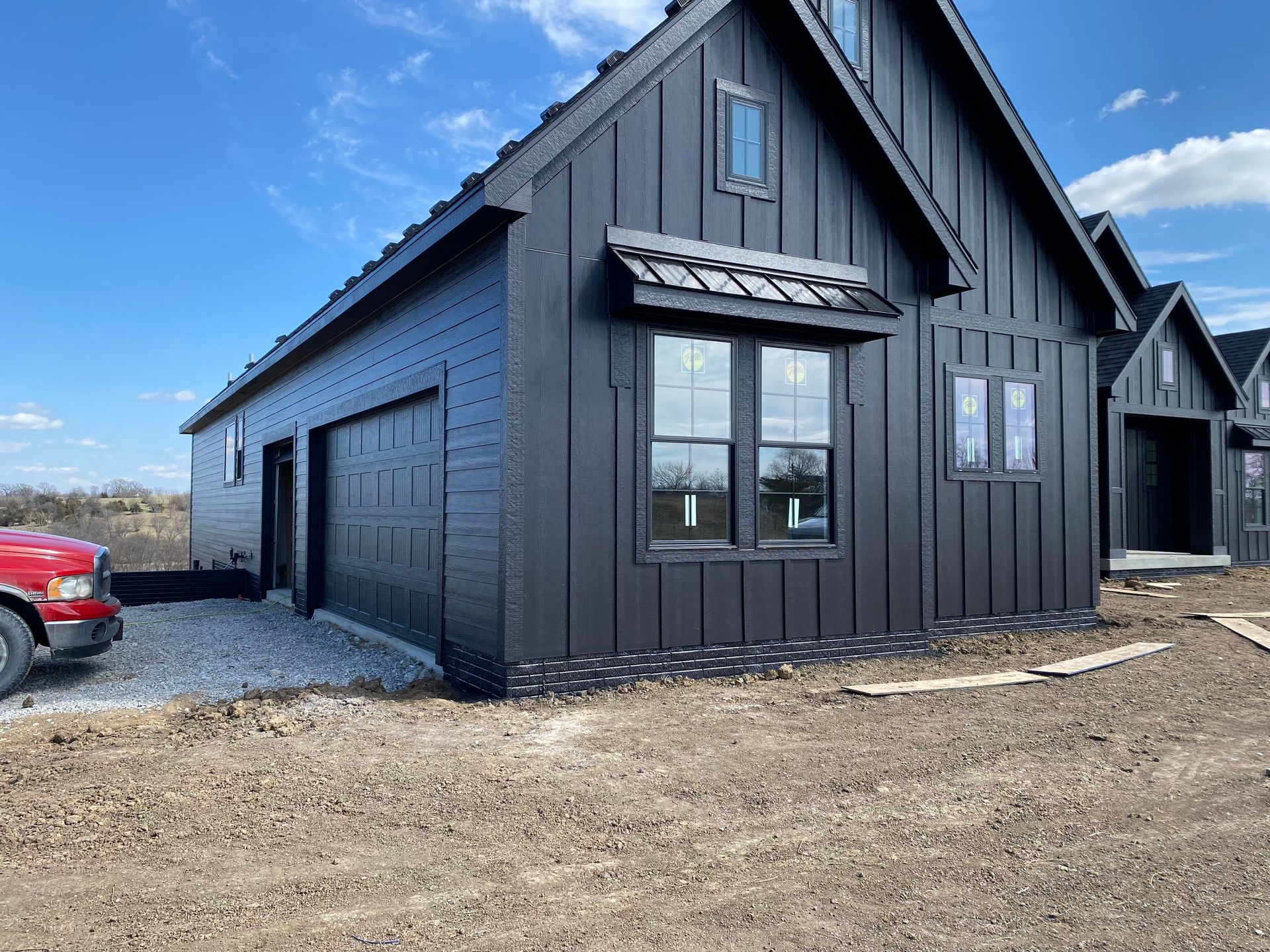 Black modern farmhouse exterior with garage and awning.