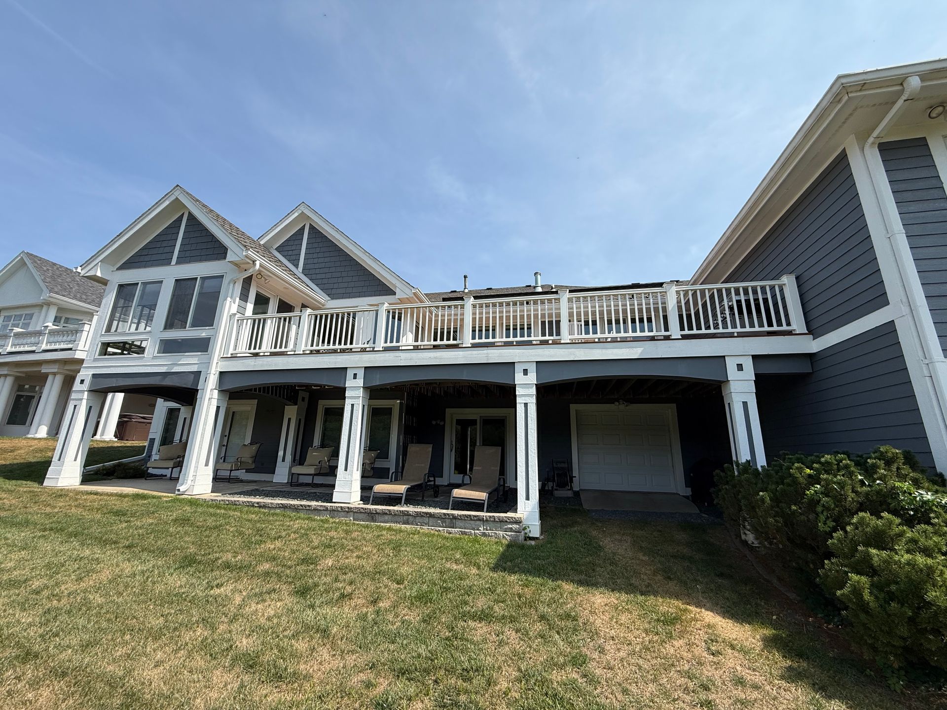 Exterior of a multi-story house with a blue facade, a large deck, and a grassy yard.