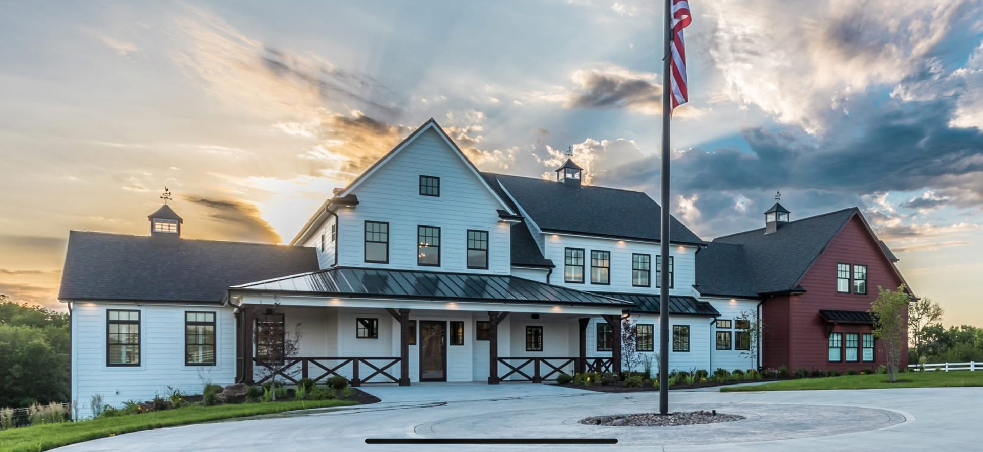 Farmhouse style building with white and red exterior under cloudy sky.