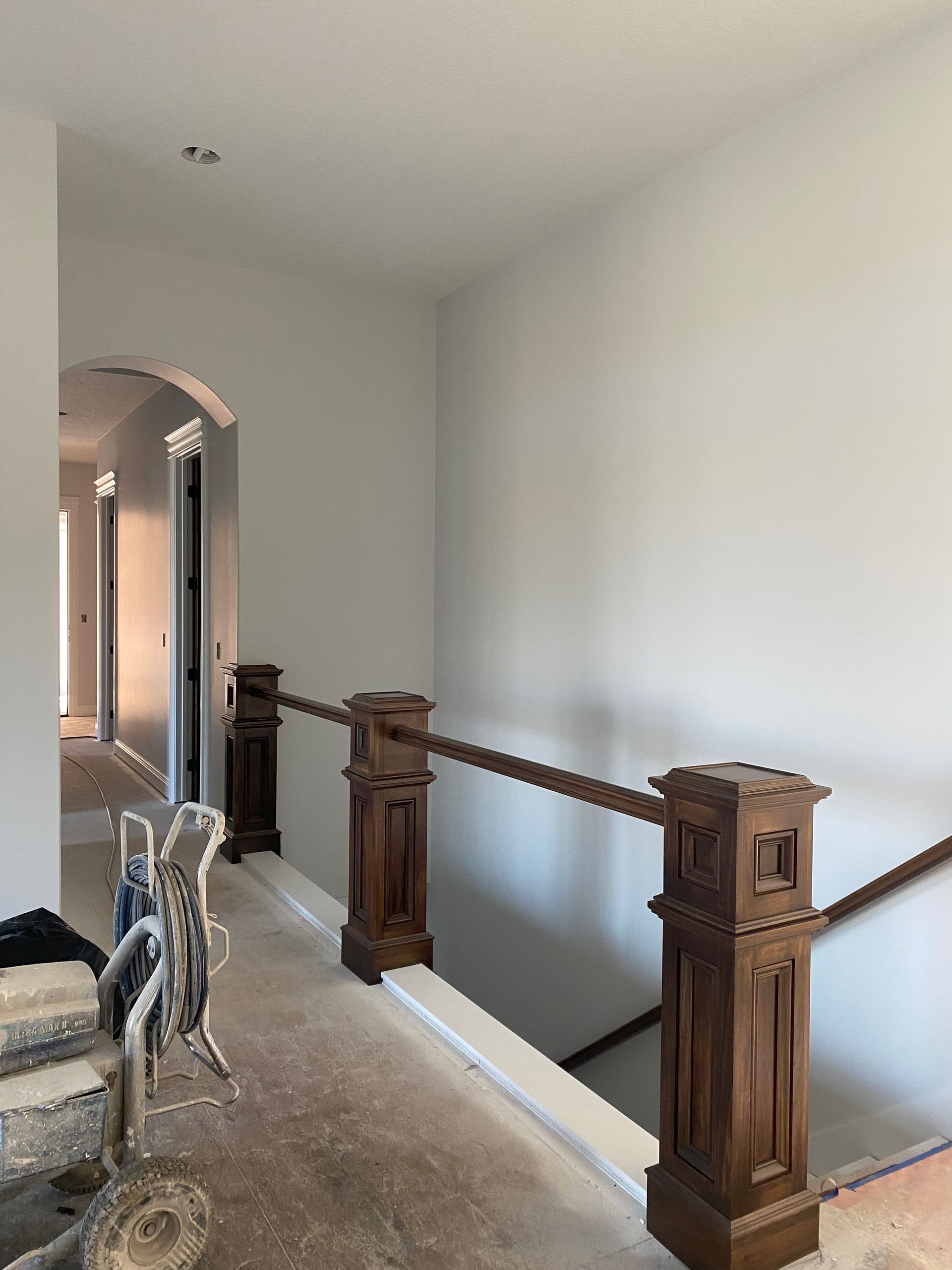 Interior hallway with stained wood railing and neutral-colored walls.