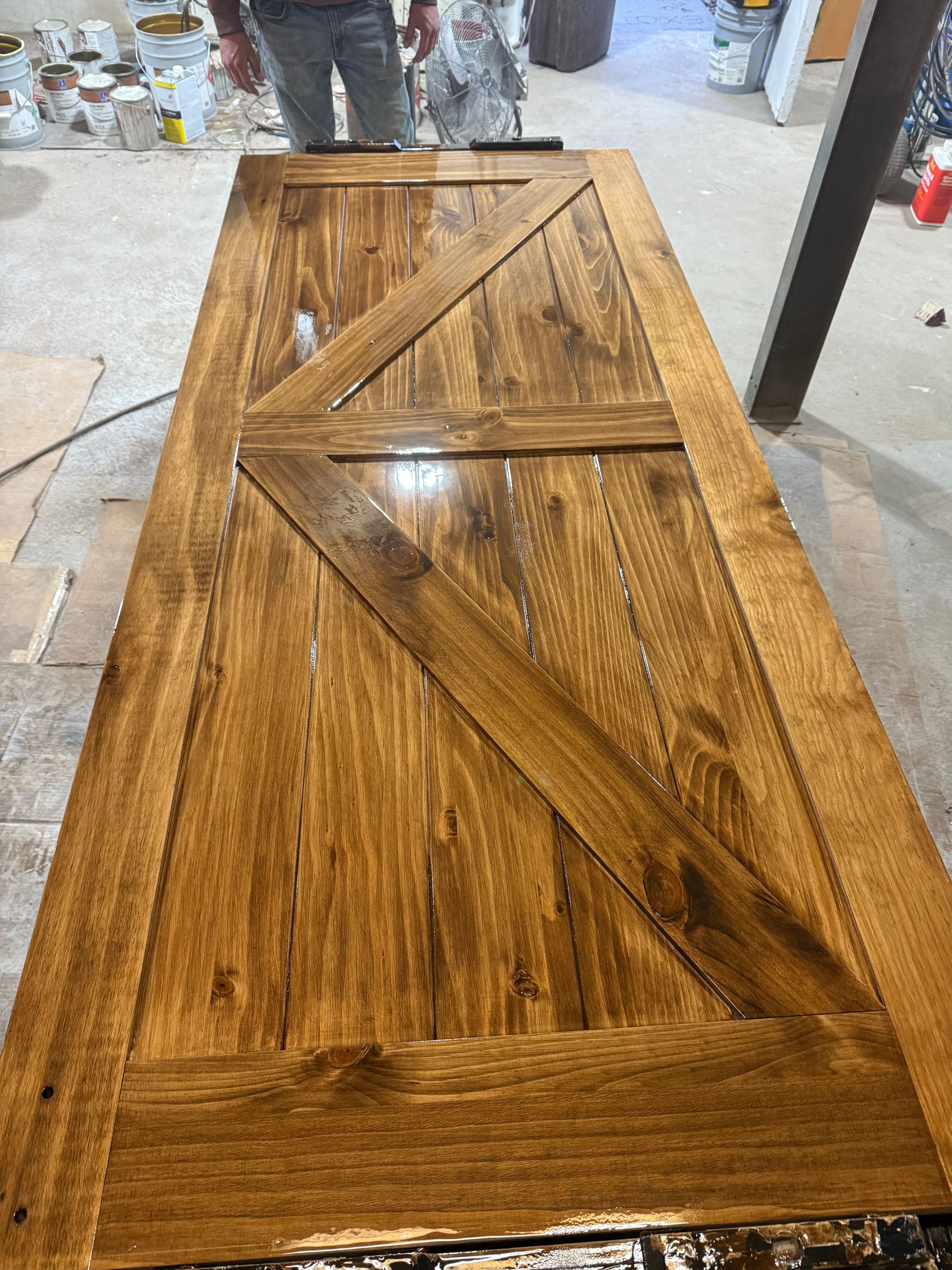 Wooden barn door with diagonal and horizontal supports, stained a warm brown color.