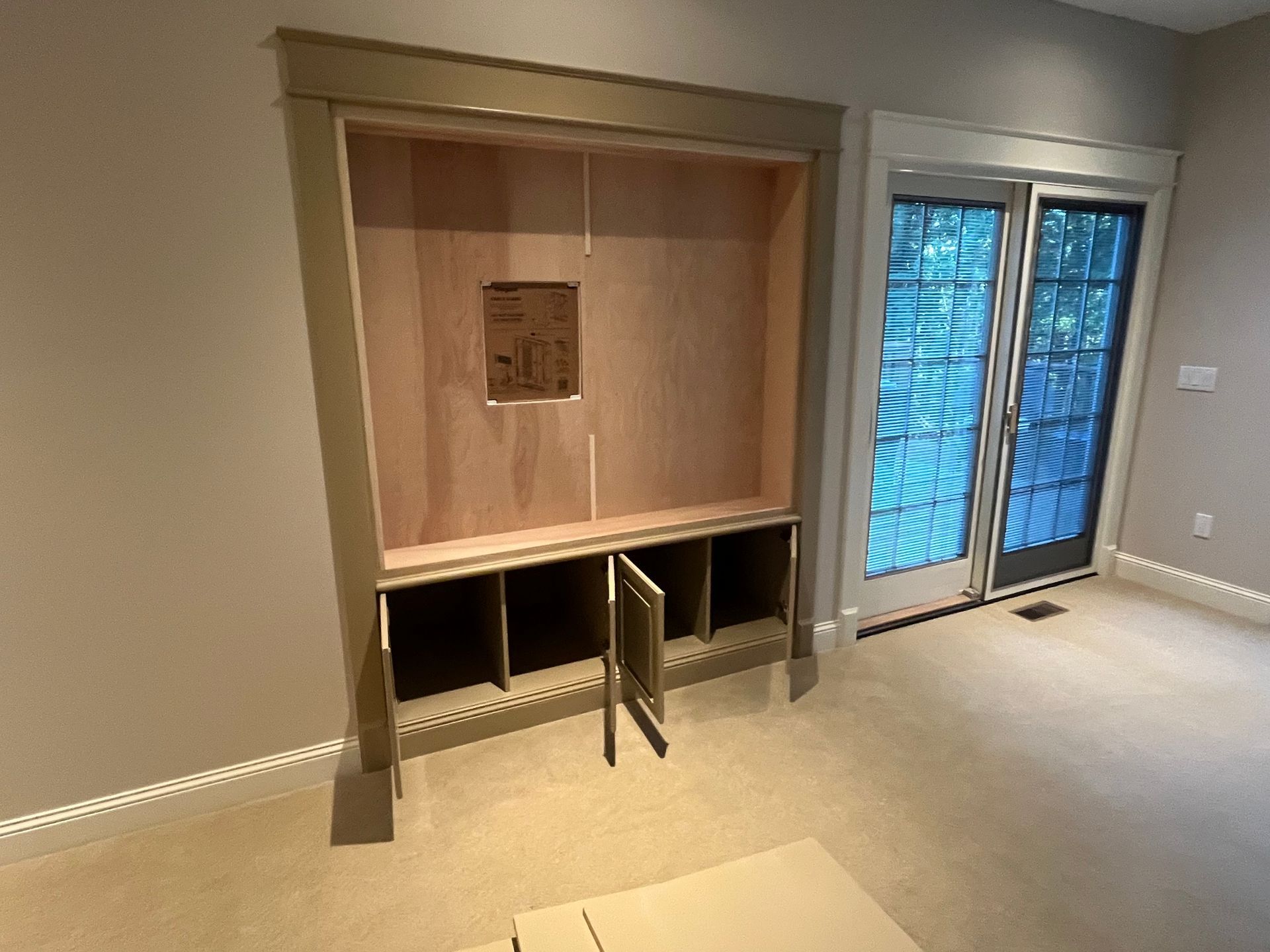 Built-in cabinet with open cubby doors, set in a room next to glass sliding doors.