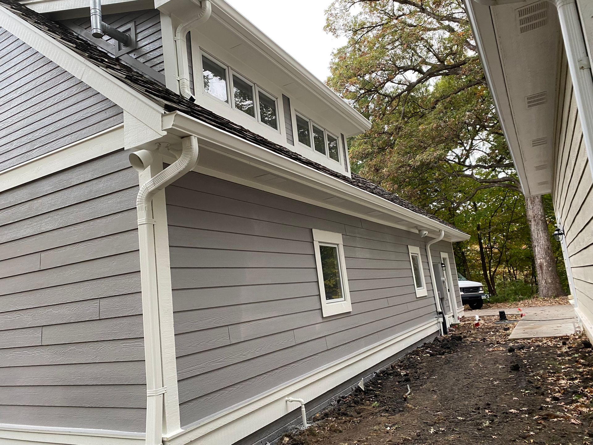 Gray house with white trim, gutters, and siding. Exterior view, natural light.