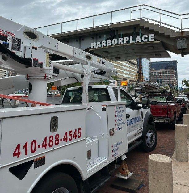 White utility truck with an extended boom arm at Harborplace, Baltimore. Phone number: 410-488-4545.