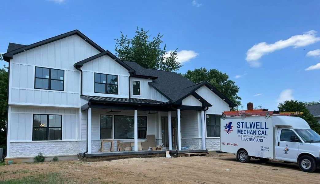 Two-story white house under construction with black trim.  White van with 