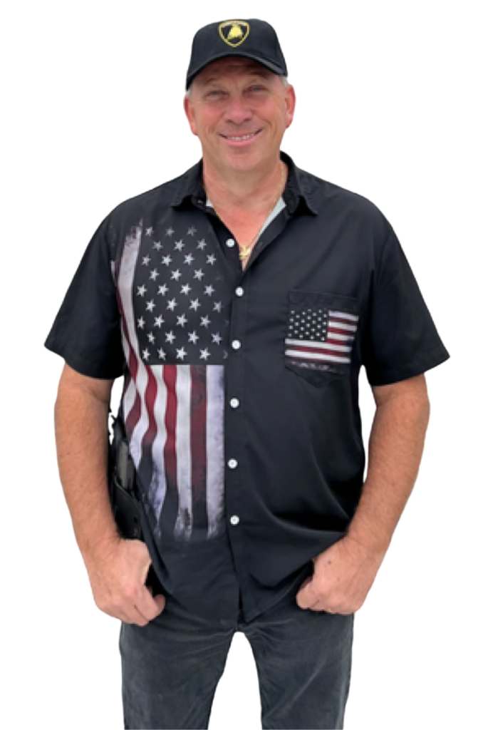 Man in American flag shirt and Lamborghini cap smiling, hands in pockets.