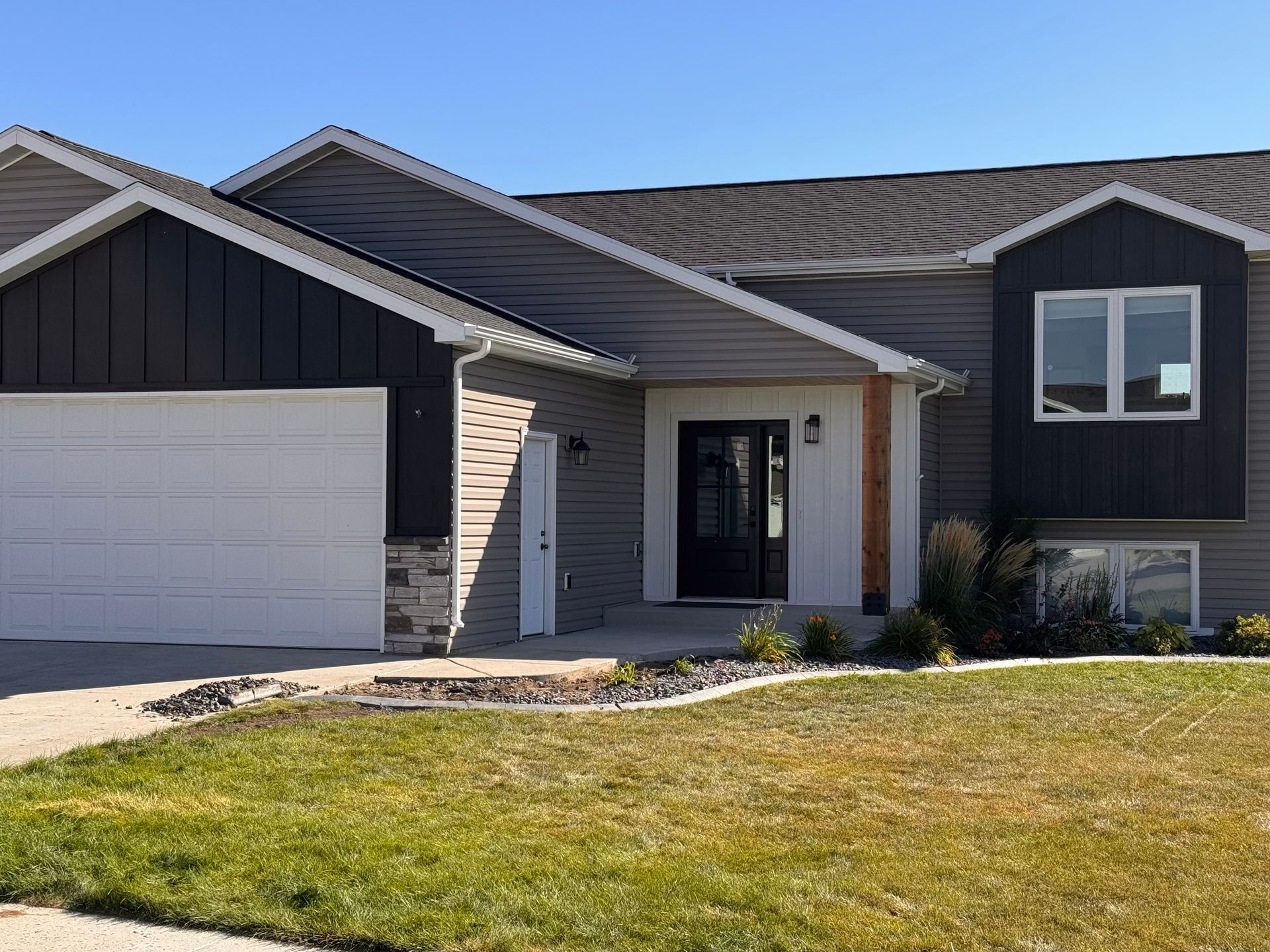 A large house with a white garage door and a large lawn in front of it.