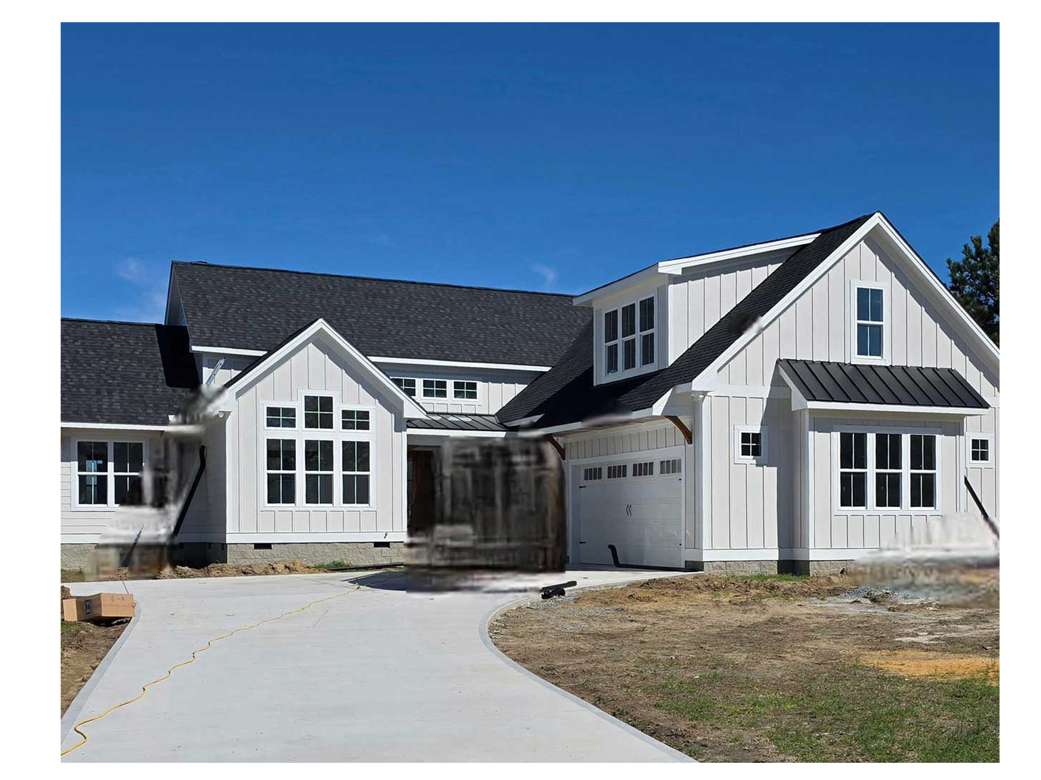 A modern white house with vertical siding, a dark roof, and a concrete driveway under a clear blue sky.